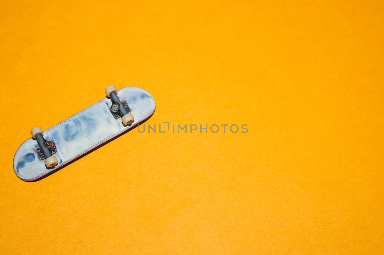 Small skateboard on yellow background. tiny skate for fingers. fingerboard close up. copy space