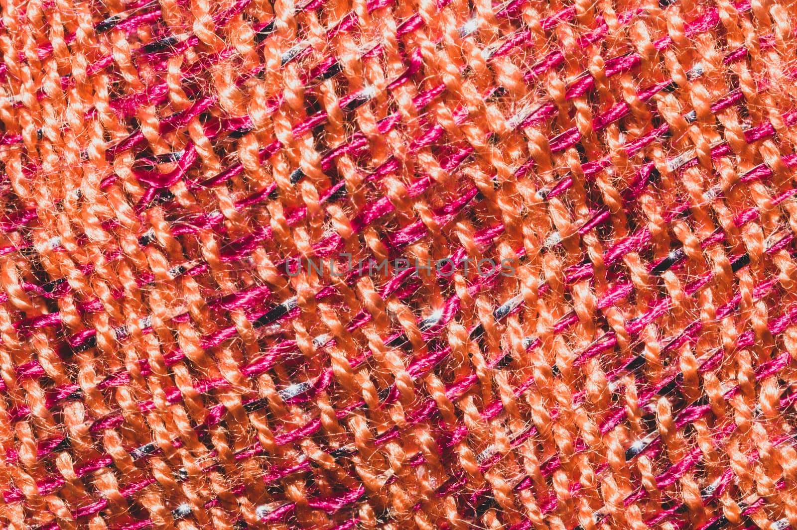 Fabric macro texture. knitted textile close up. woven background. woolen material. weaving orange and red threads