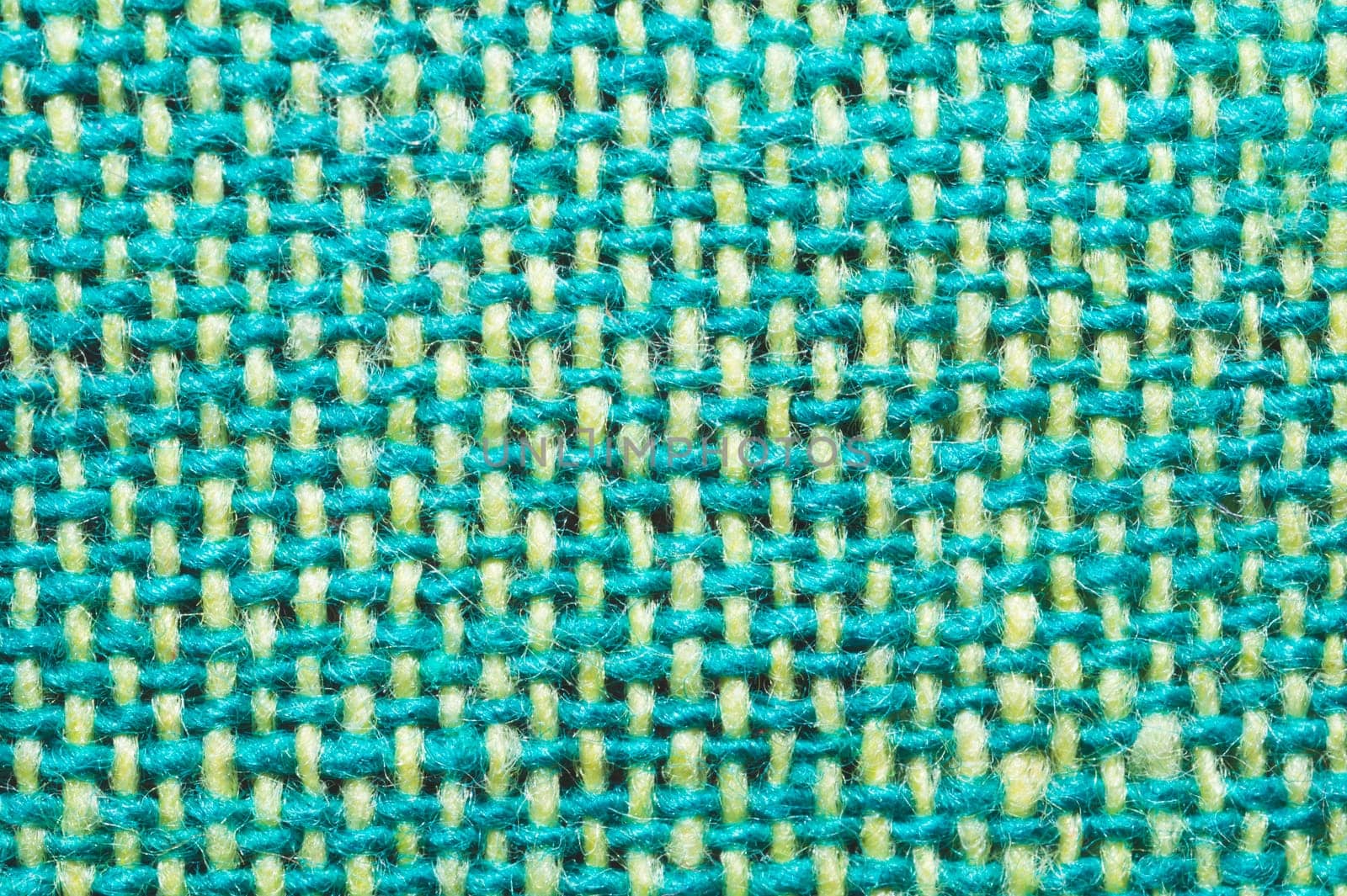 Fabric macro texture. knitted textile close up. woven background. woolen material. weaving green and yellow threads