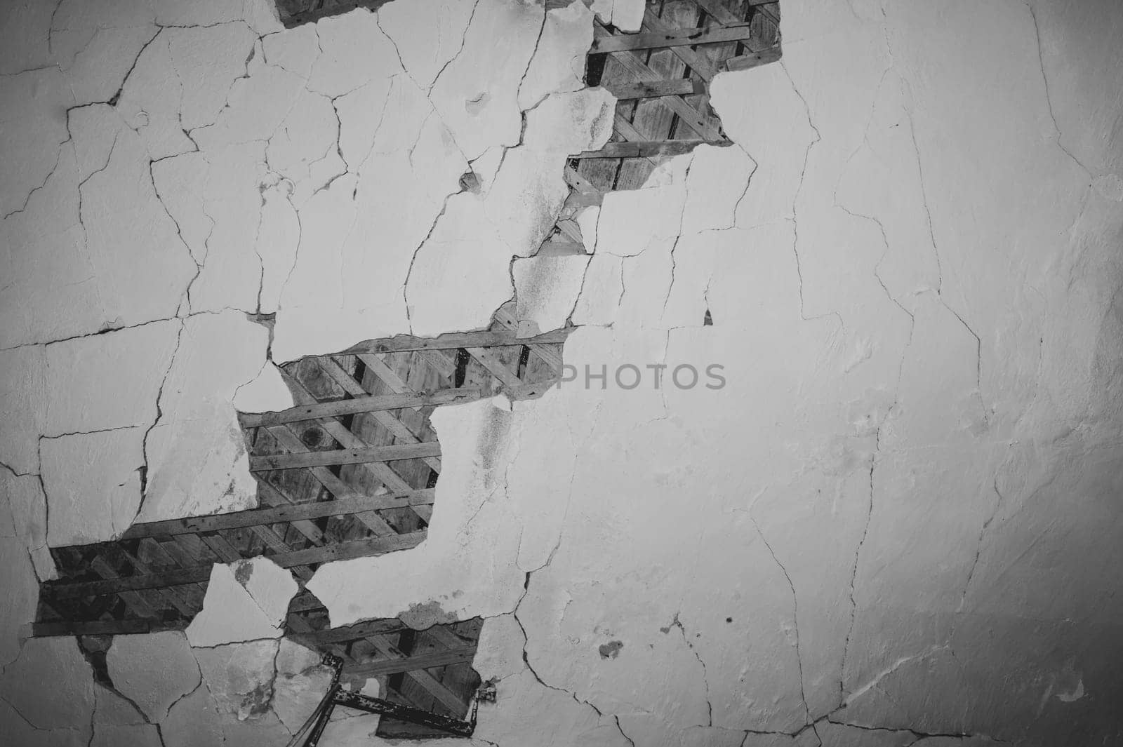 Dilapidated ceiling of an old house. damaged wall with a hole with timber frame. abstract background of ruined surface