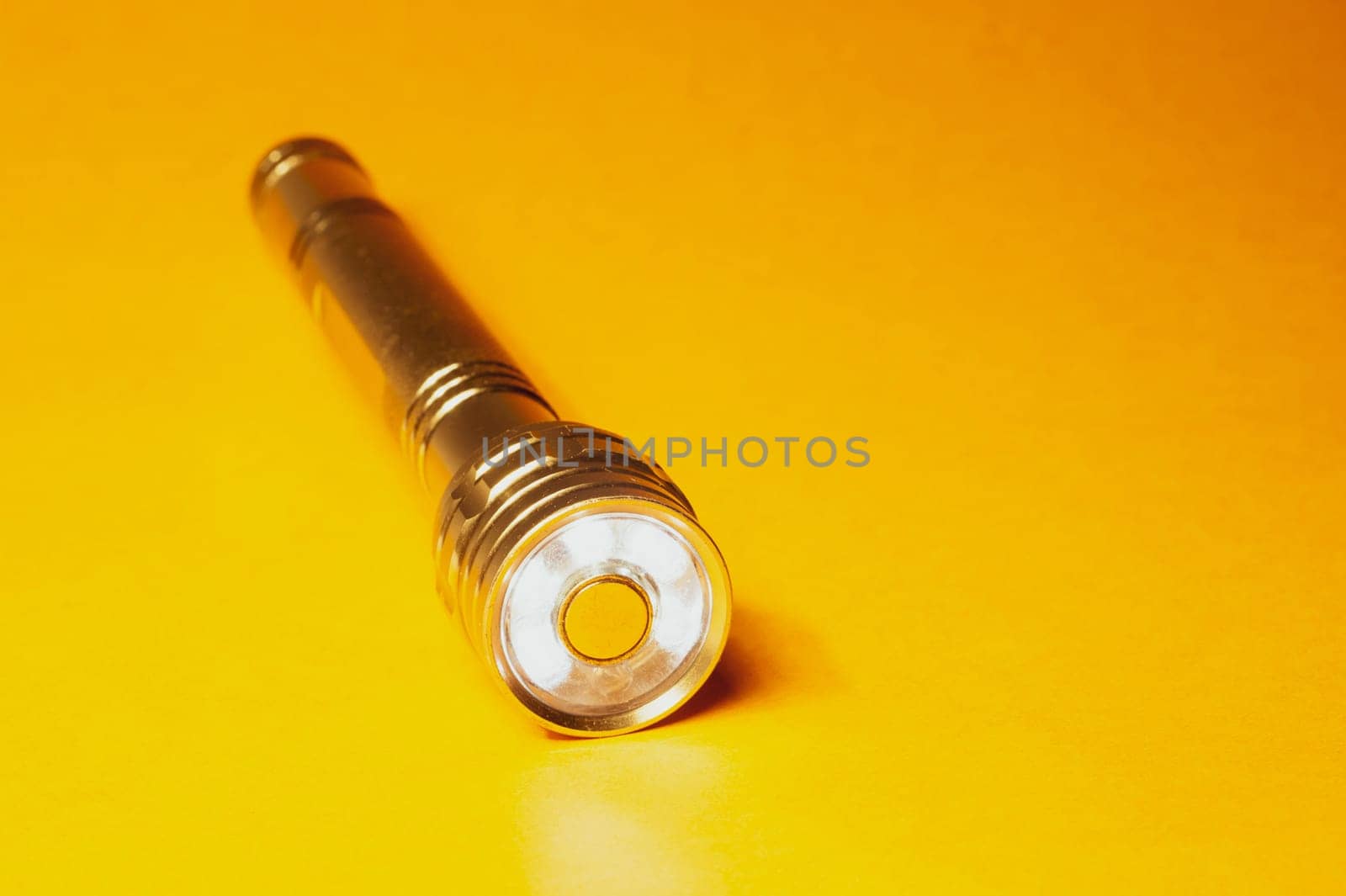Metal flashlight on a yellow background