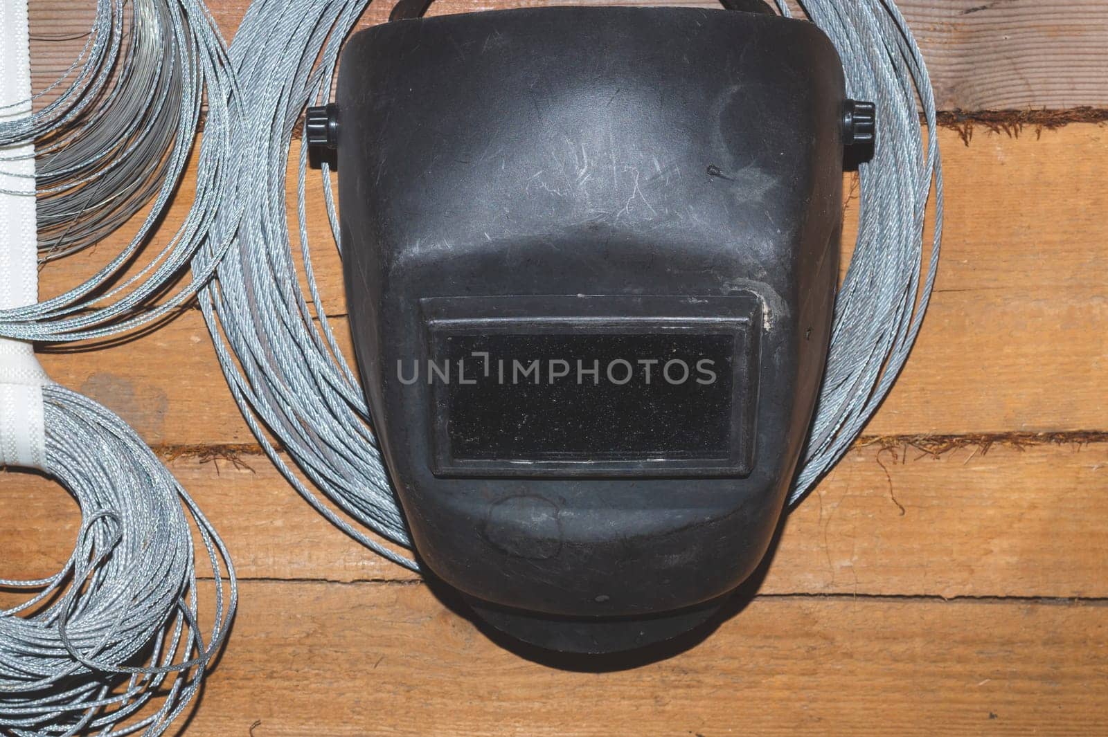 Protective welding mask hanging on a wooden wall. hanks of steel rope. helmet for ironworker