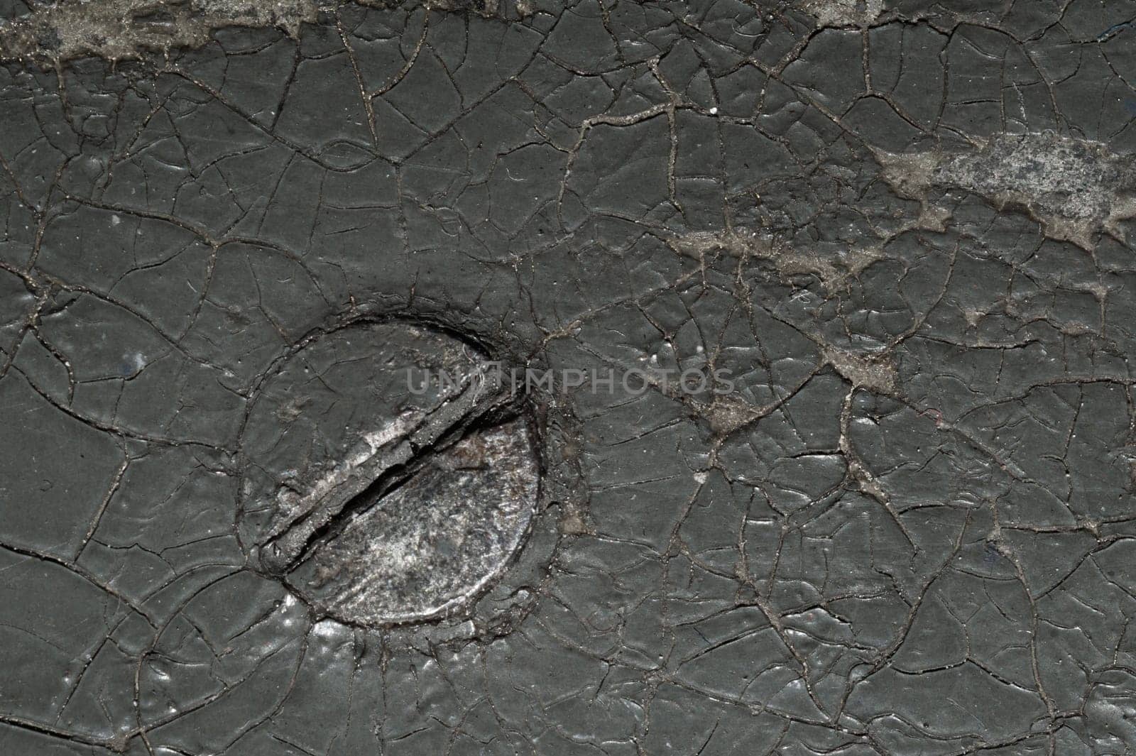Cracked black coating on wooden surface. grunge background. metal nail covered with paint. shabby wood texture. spots and scratches