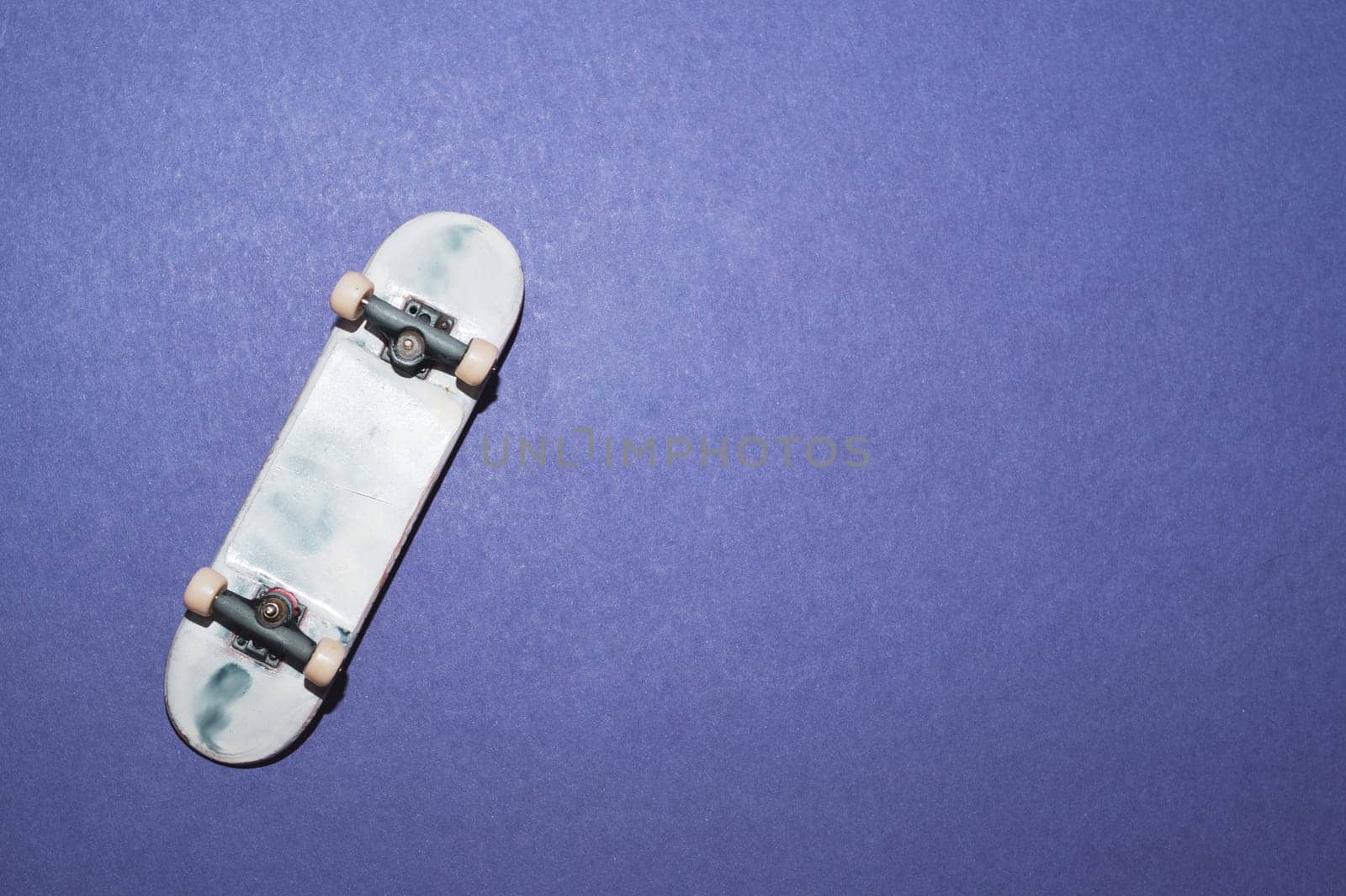 Small skateboard on blue background. tiny skate for fingers. fingerboard close up. copy space