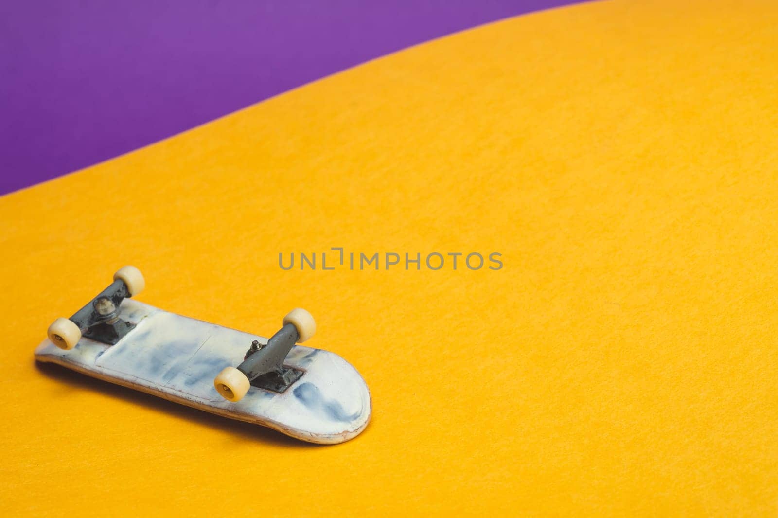 Small skateboard on color background. tiny skate for fingers. fingerboard close up. home leisure concept. copy space