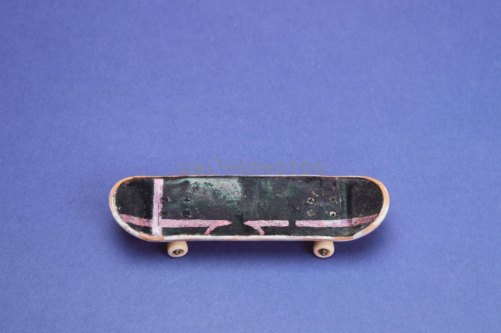 Small skateboard on blue background. tiny skate for fingers. fingerboard close up. copy space