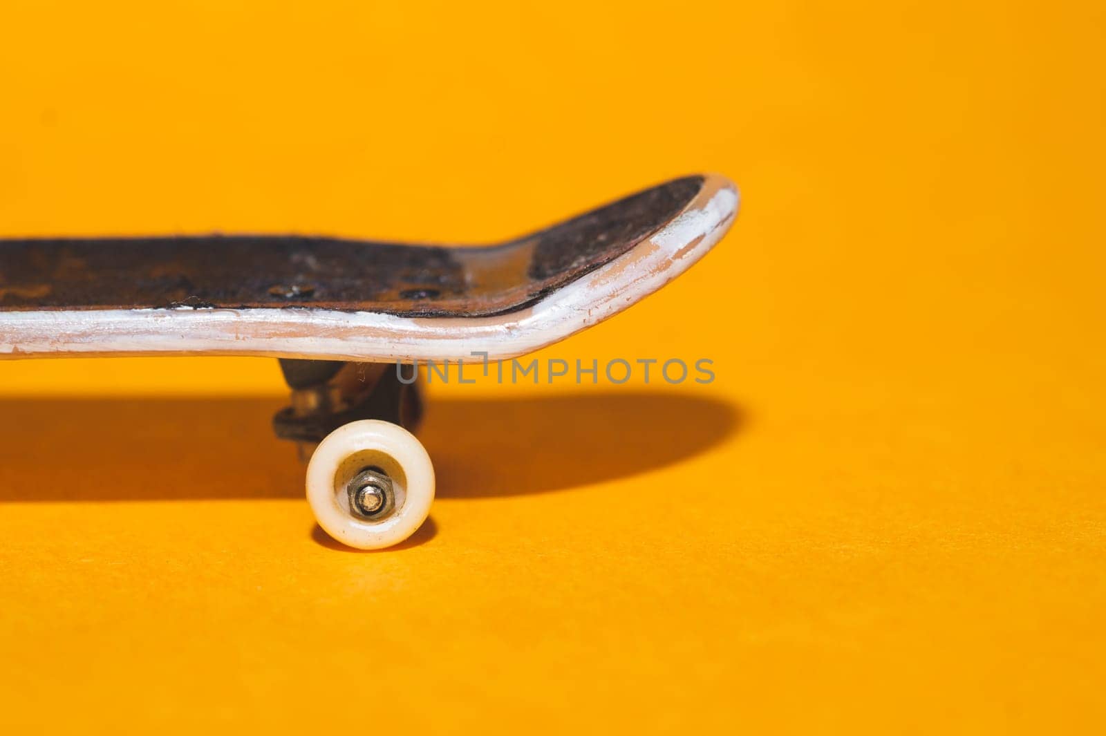 Small skateboard on yellow background. tiny skate for fingers. fingerboard close up. copy space