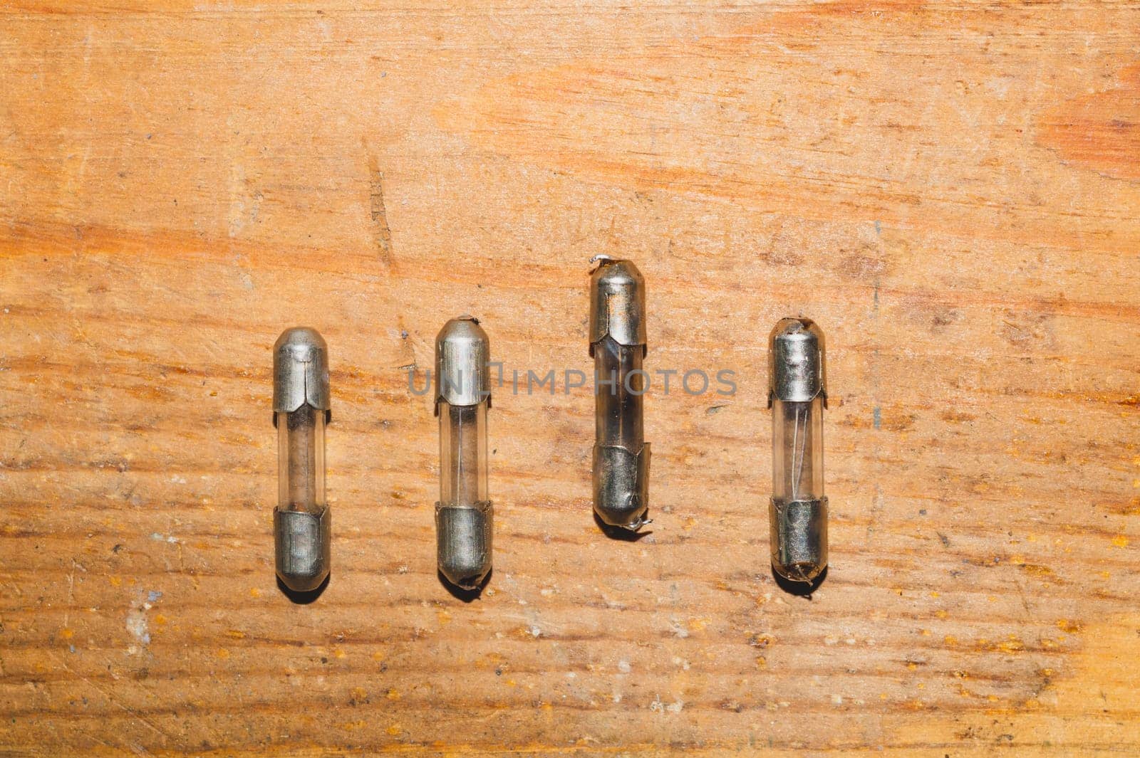 Row of fuses with burned out fuse on wooden background. safety device for overcurrent protection. protection of an electrical circuit
