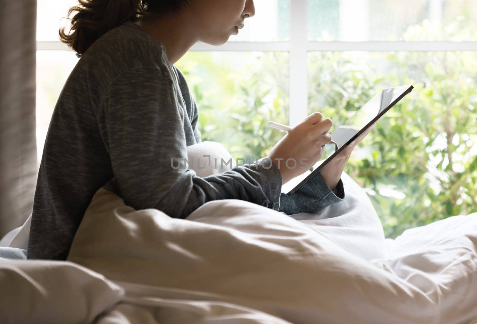 Working at morning, Worker women using stylus pen on digital tablet on bed
