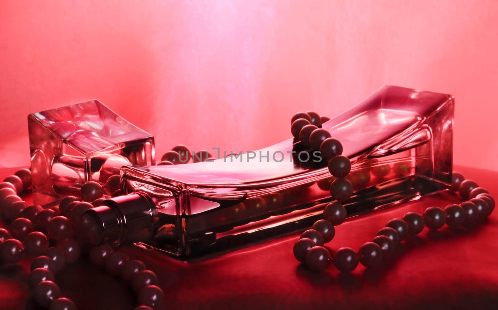 Bottle of perfume and pearls on purple silk