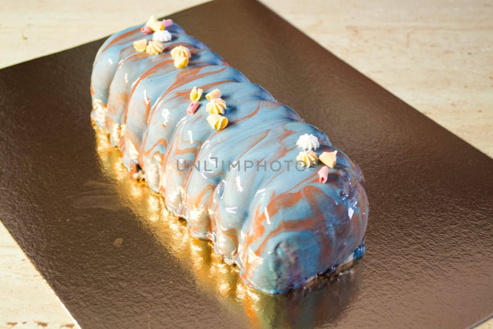 Minimalistic french mousse cake with blue mirror glaze and edible decor.