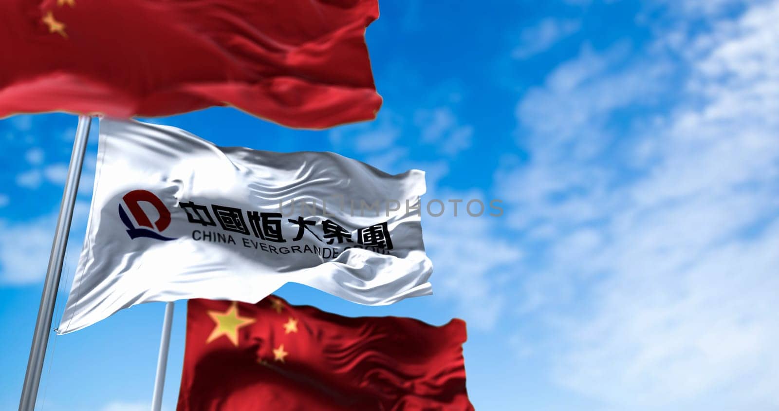 Guangzhou, China, October 2021: The flags of the Evergrande Group and China waving in the wind. Three flags. Evergrande is the second largest property developer in China by sales