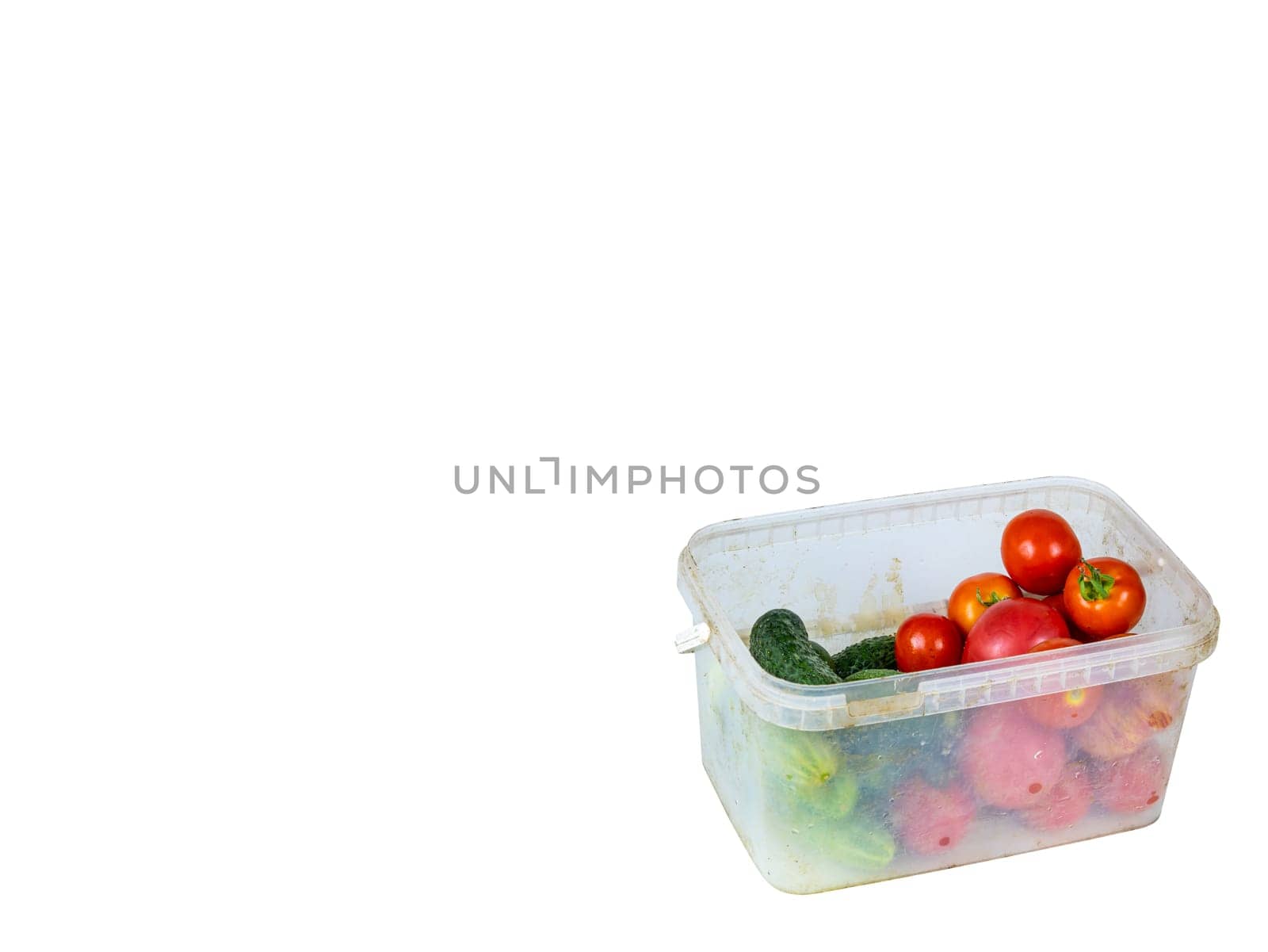 Vegetables, cucumbers and tomatoes in a plastic tray. Green cucumber. Red tomato. Harvesting vegetables. Plastic dishes. White background. Shop window. Agricultural business.
