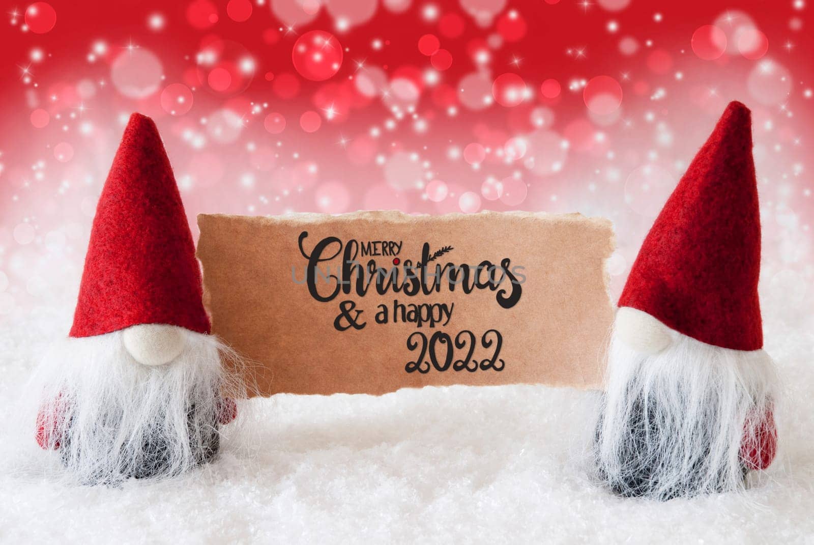 Sign With English Calligraphy Merry Christmas And A Happy 2022. Santa Claus With Red Hat. Snow With Red Sparkling Background