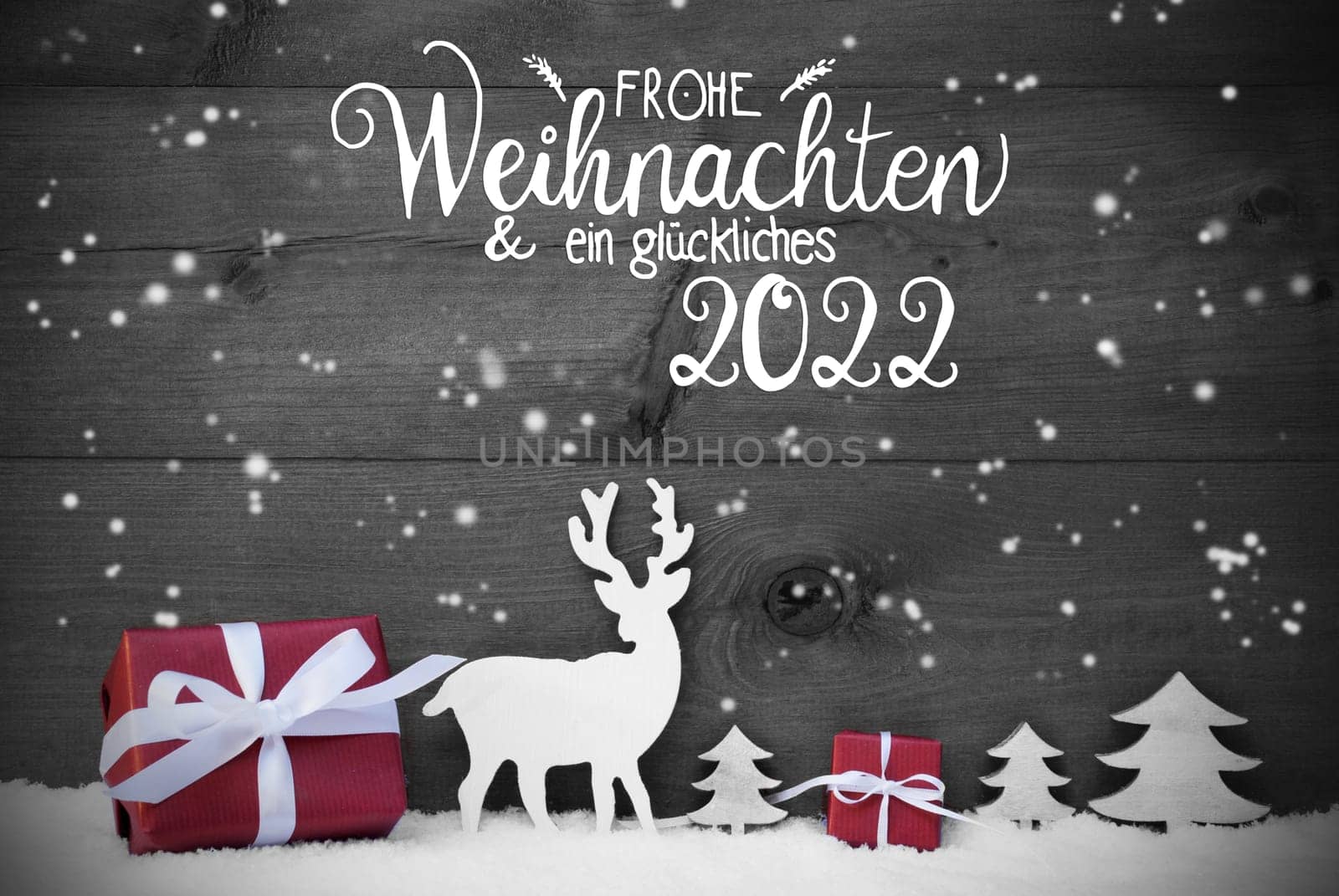 German Calligraphy Frohe Weihnachten Und Ein Glueckliches 2022 Means Merry Christmas And A Happy 2022. Red Christmas Decoration Like Tree, Gift, And Reindeer. Black Wooden Background With Snowfalkes