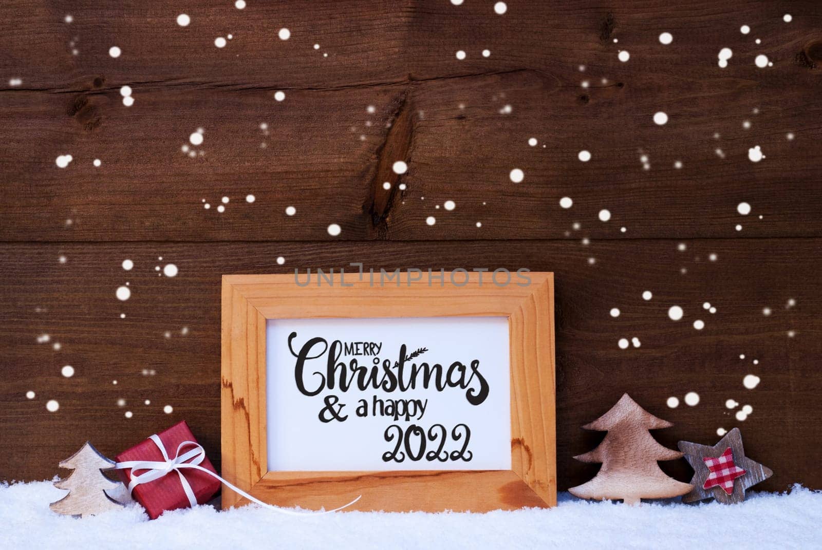 Frame With English Calligraphy Merry Christmas And A Happy 2022. Christmas Decoration Like Gift, Tree And Star. Wooden Background With Snow