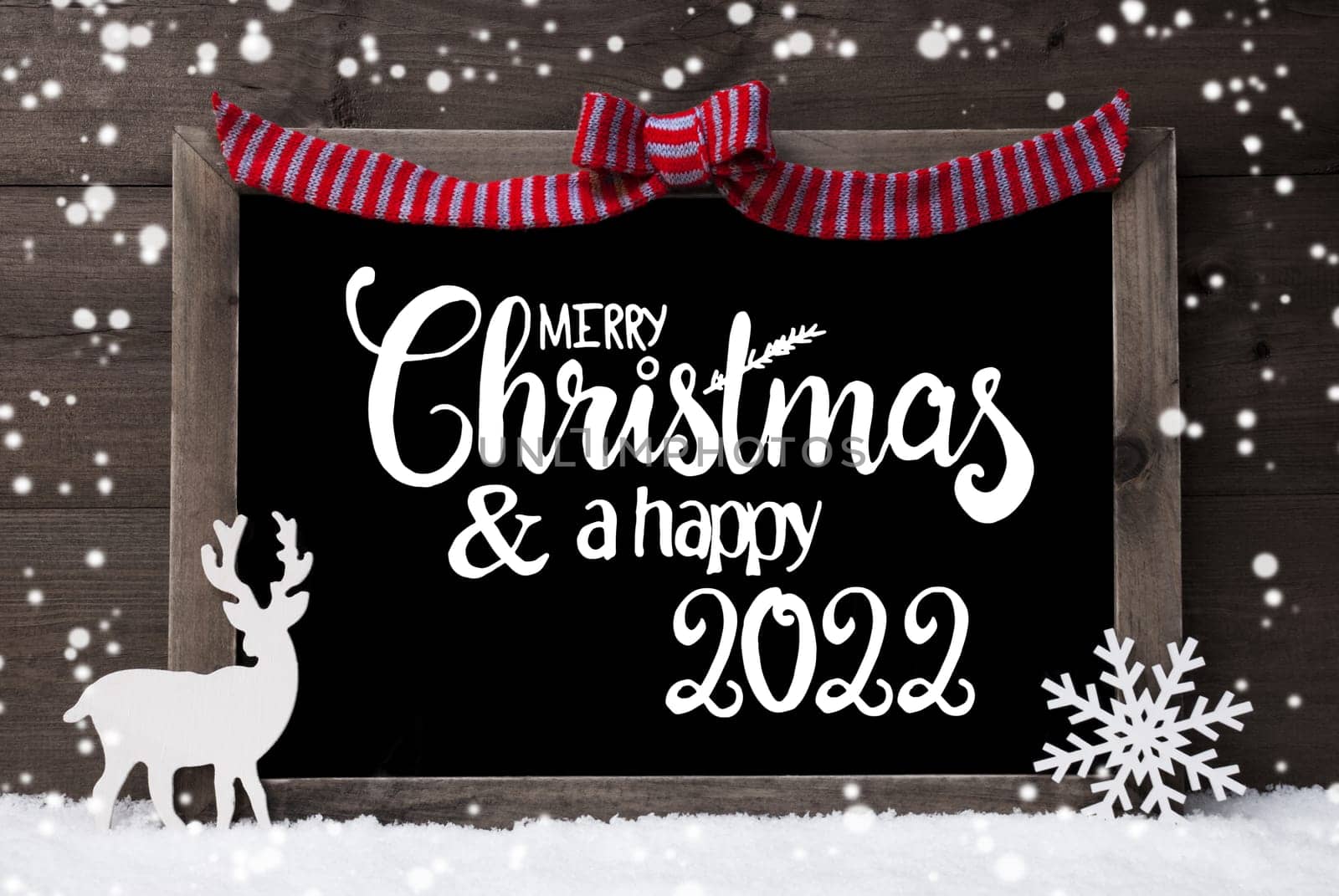 Chalkboard With English Calligraphy Merry Christmas And A Happy 2022. Decoration Like Deer And Bow. Gray Wooden Background With Snow And Snowflakes