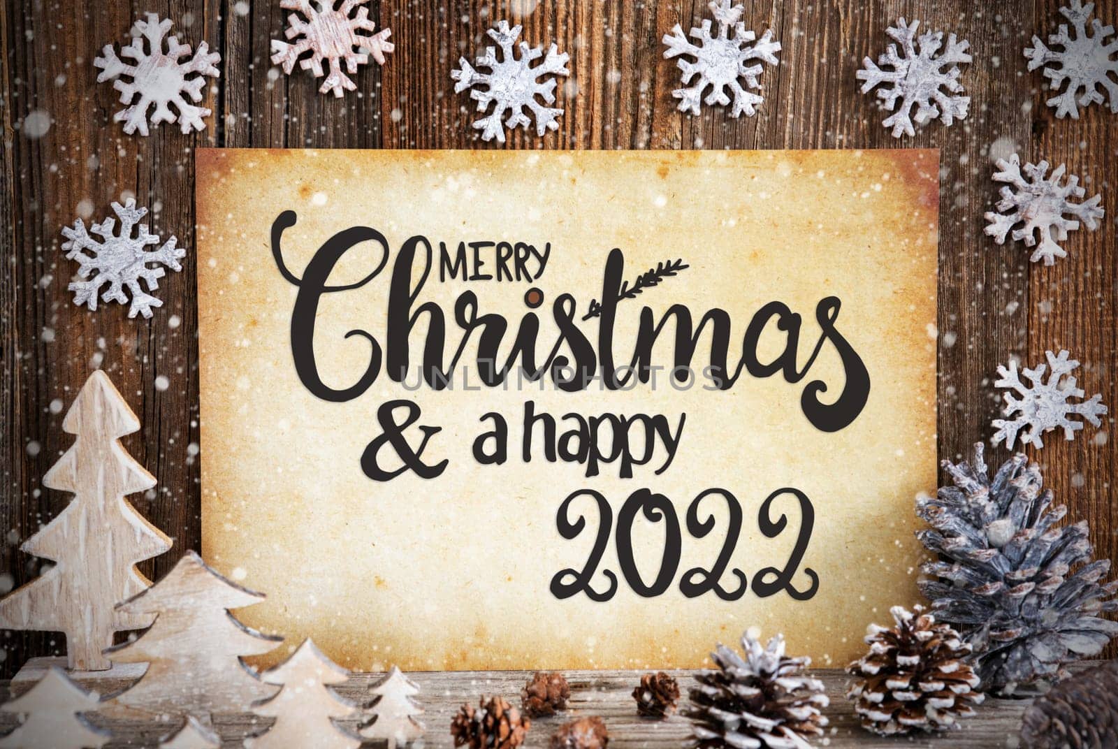 Old Paper With English Text Merry Christmas And Happy 2022. Christmas Decoration Like Tree, Fir Cone And Snow. Brown Wooden Background