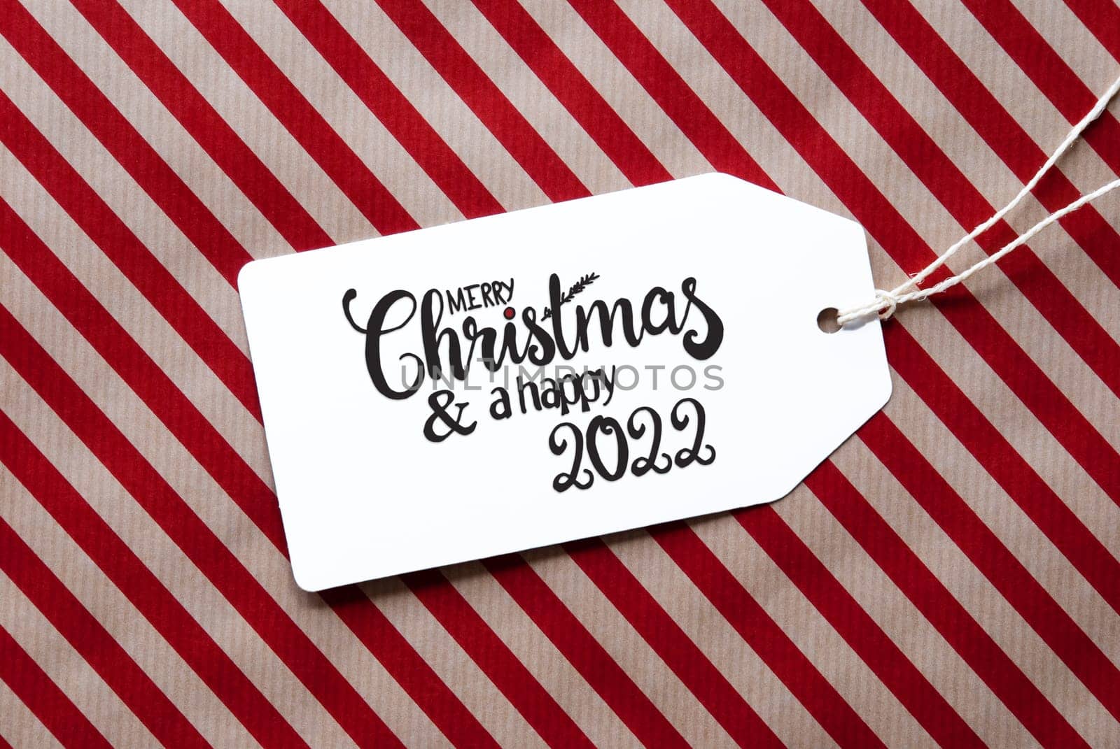 Label With English Calligraphy Merry Christmas And A Happy 2022. Red Wrapping Paper As Background