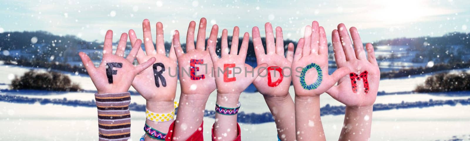 Children Hands Building Colorful English Word Freedom. Snowy Winter Background With Snowflakes