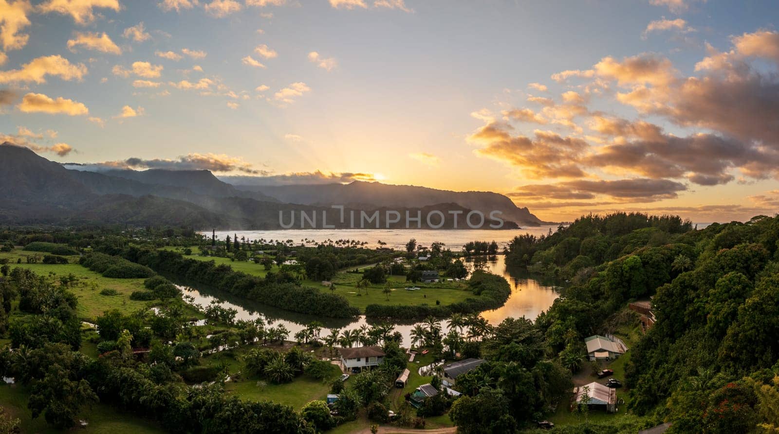 A vibrant aerial view of sunset clouds over the lush landscape of Hanalei Bay, framed by majestic mountains in Kauai, Hawaii.