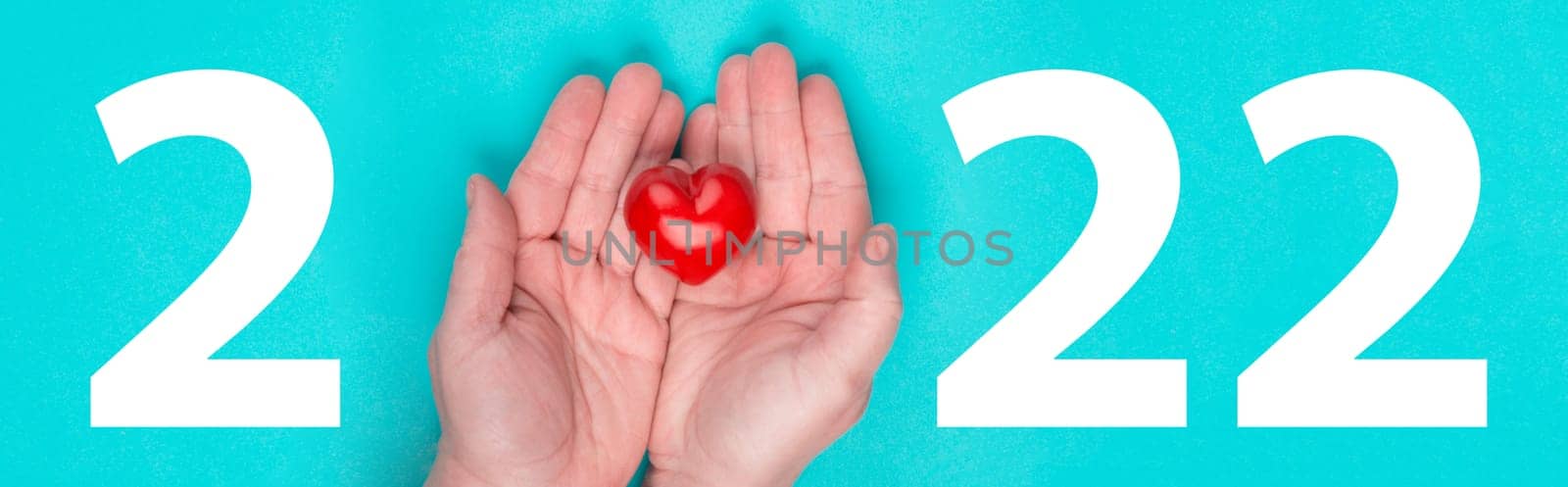 Year 2022, hand with a red heart, blue colored background, calendar