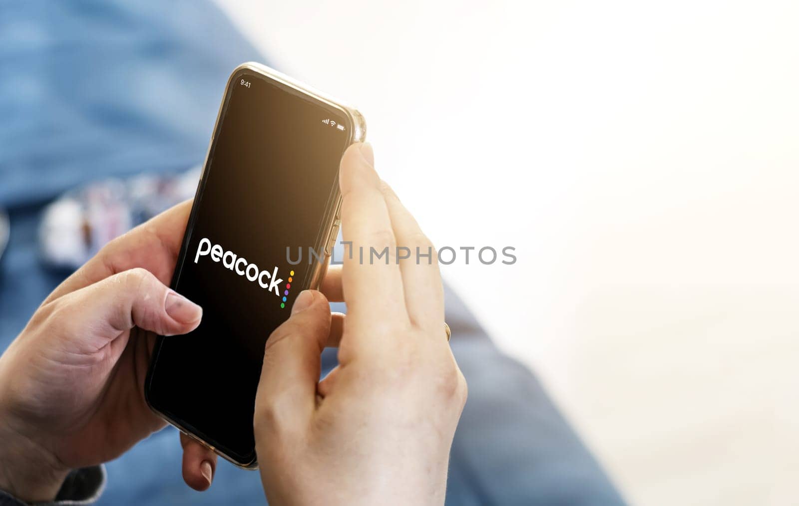 New York, USA, September 2021: Woman holding a smart phone with the Peacock TV mobile app on the screen. Peacock is an American video streaming service