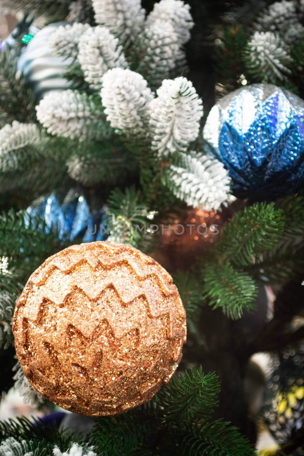 Closeup of festively decorated Christmas tree with bright blue and beige balls. Vertical image