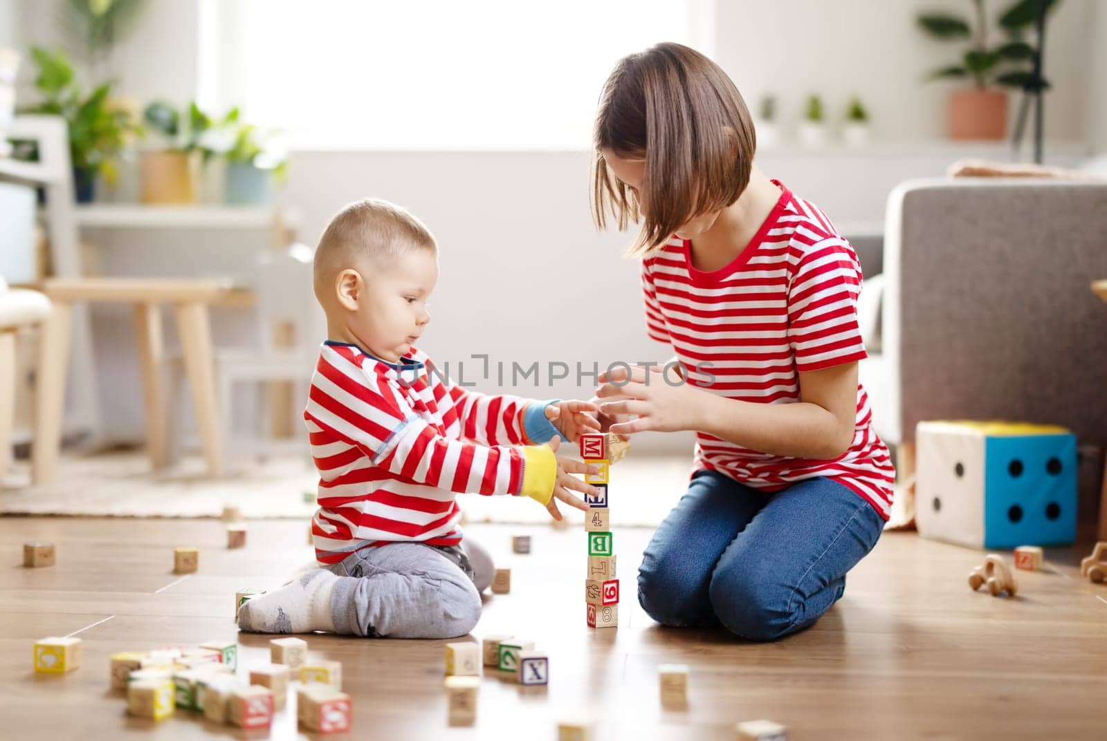 Sister and brother playing with toys together on the floor indoors. Concept of the family relationship.