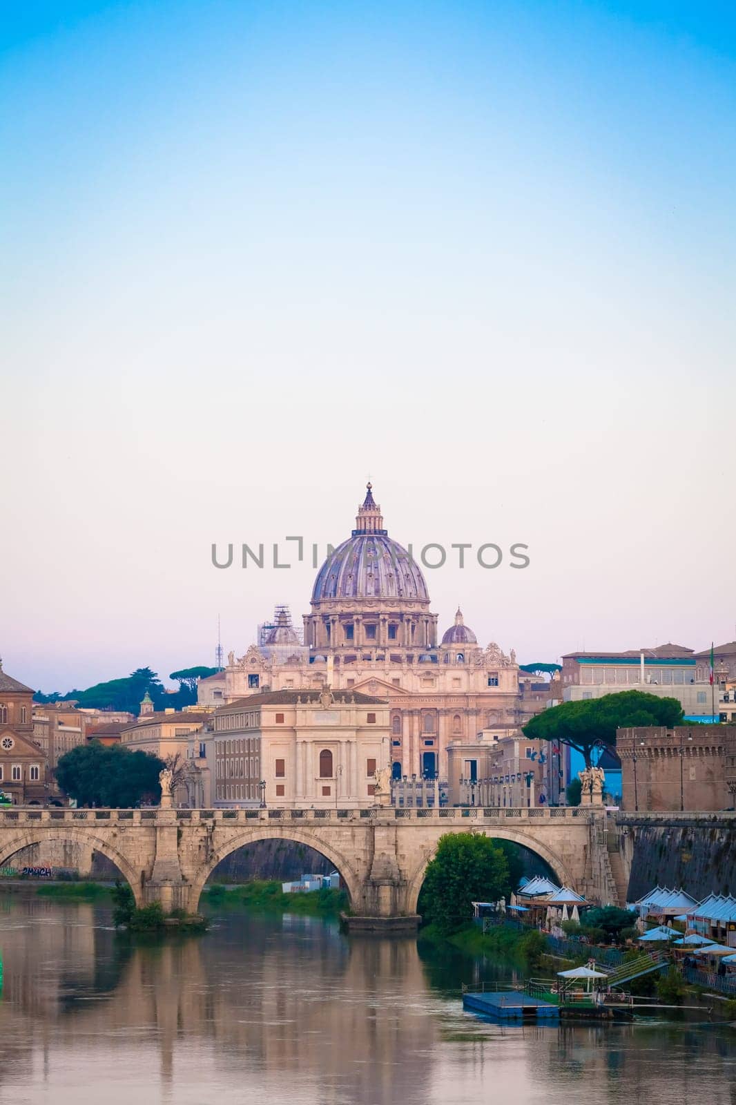 ROME, ITALY - JUNE 2020: sunset panorama on Tiber river bridge with Saint Peter Cathedral dome (Vatican City) in background - Rome, Italy