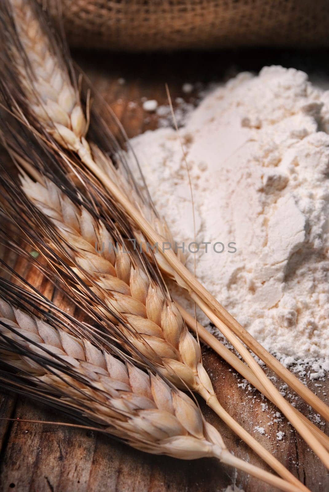 Wheat ears and flour sack on grunge wooden board
