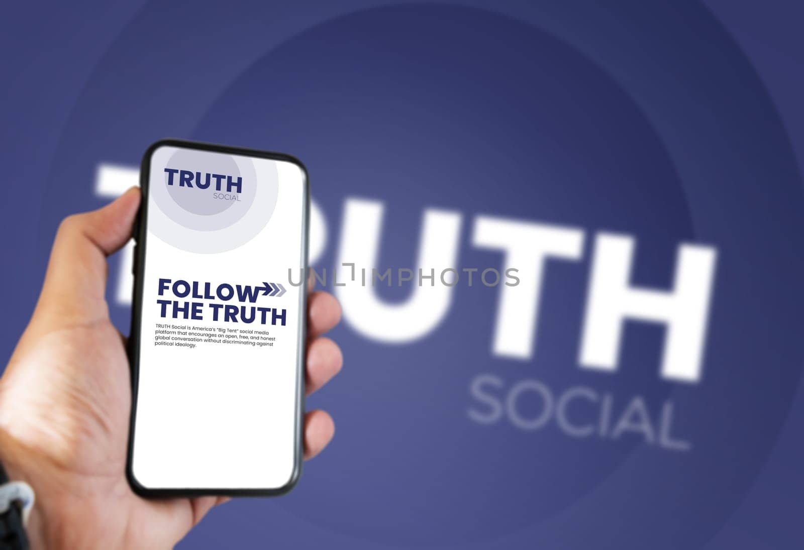 New York, USA, Oct 2021: hand holding a phone with the Truth Social mobile app on the screen and the logo blurred in the background. Truth Social is a social media platform launched by Donald Trump
