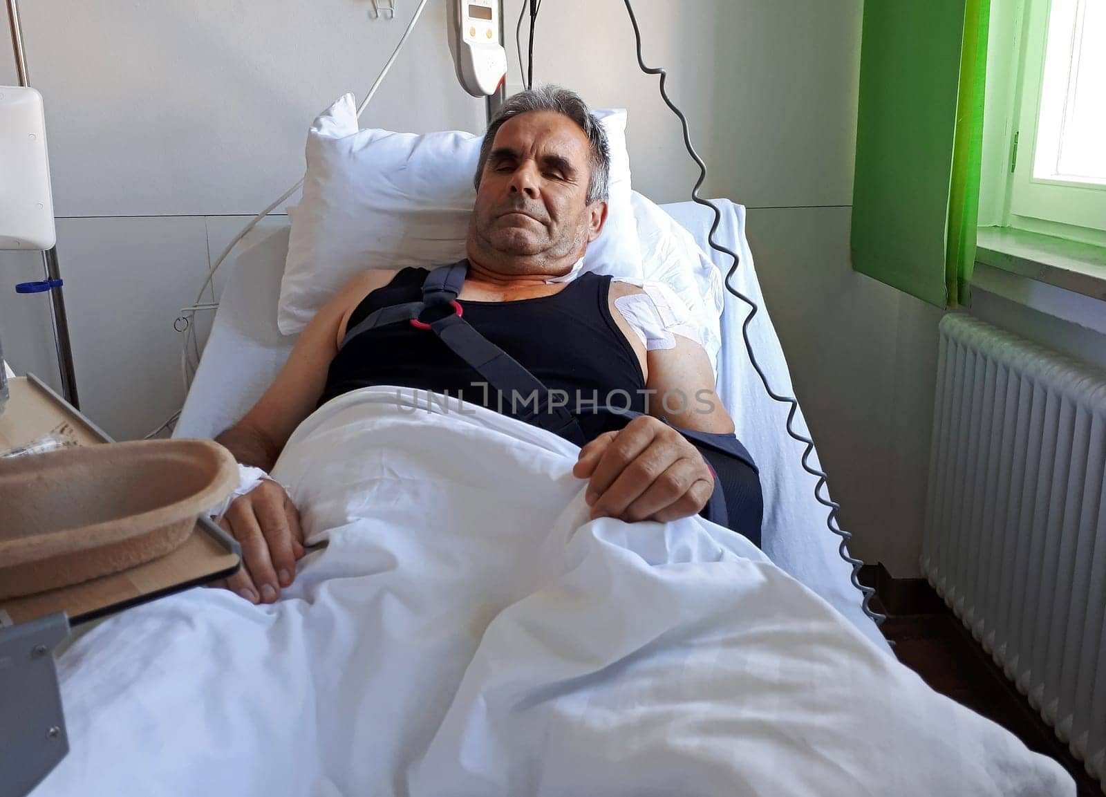 A man lies in a bed in the hospital after an operation