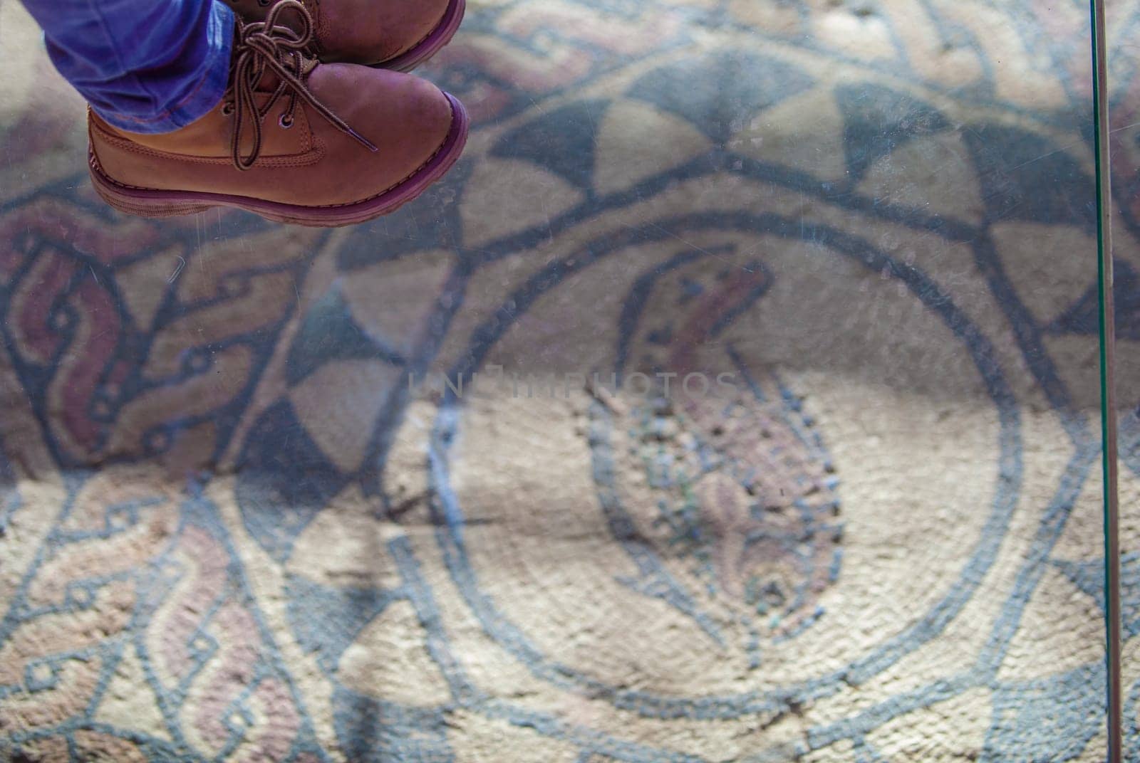 Merida, Spain - Dec 12th, 2020: Child feet over glass floor of Amphitheatre House mosaics, Merida. Extremadura, Spain