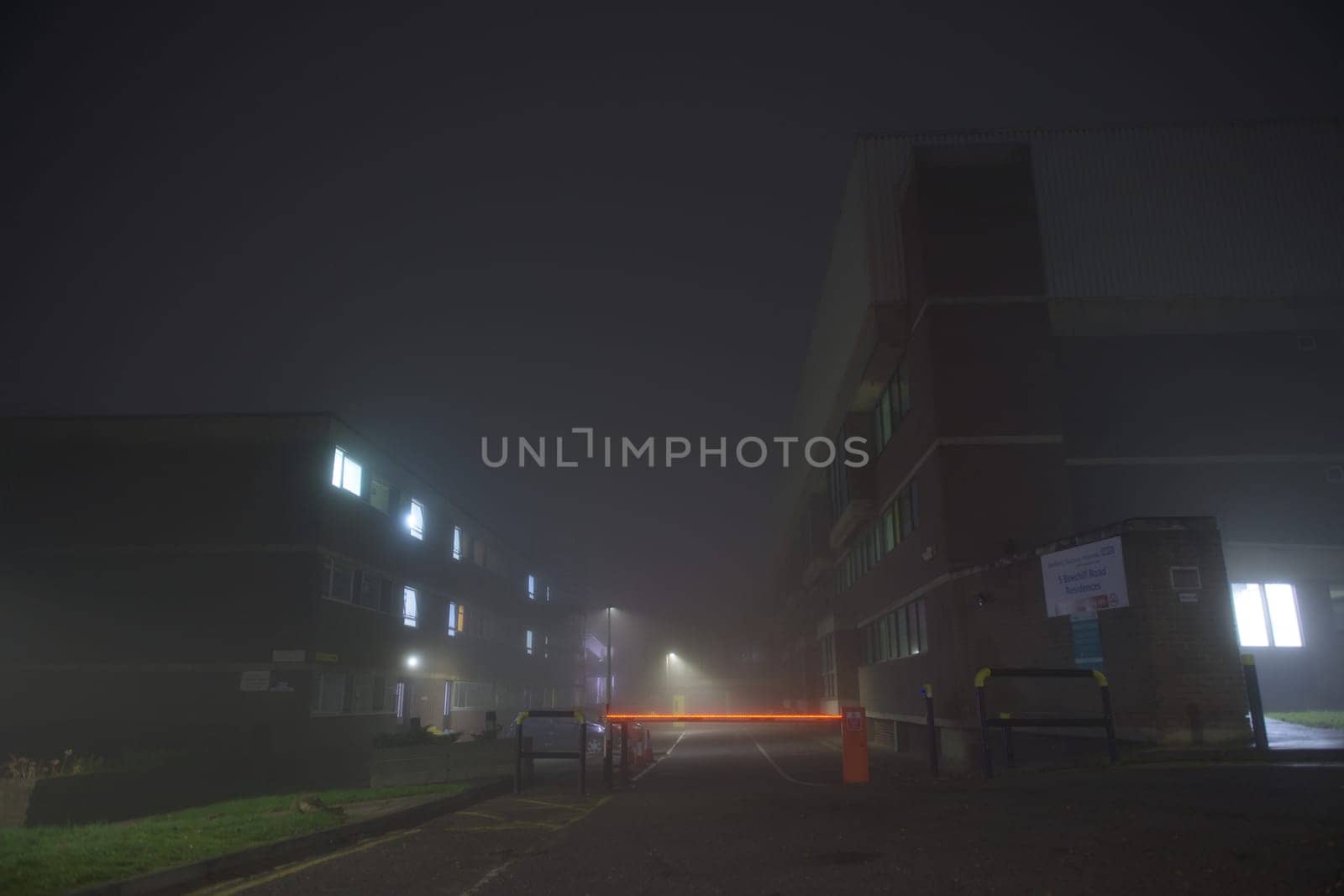 Sheffield, United Kingdom, 8th November, 2020: Hallamshire hospital accommodation at night with heavy fog weather. Illuminated traffic barrier.
