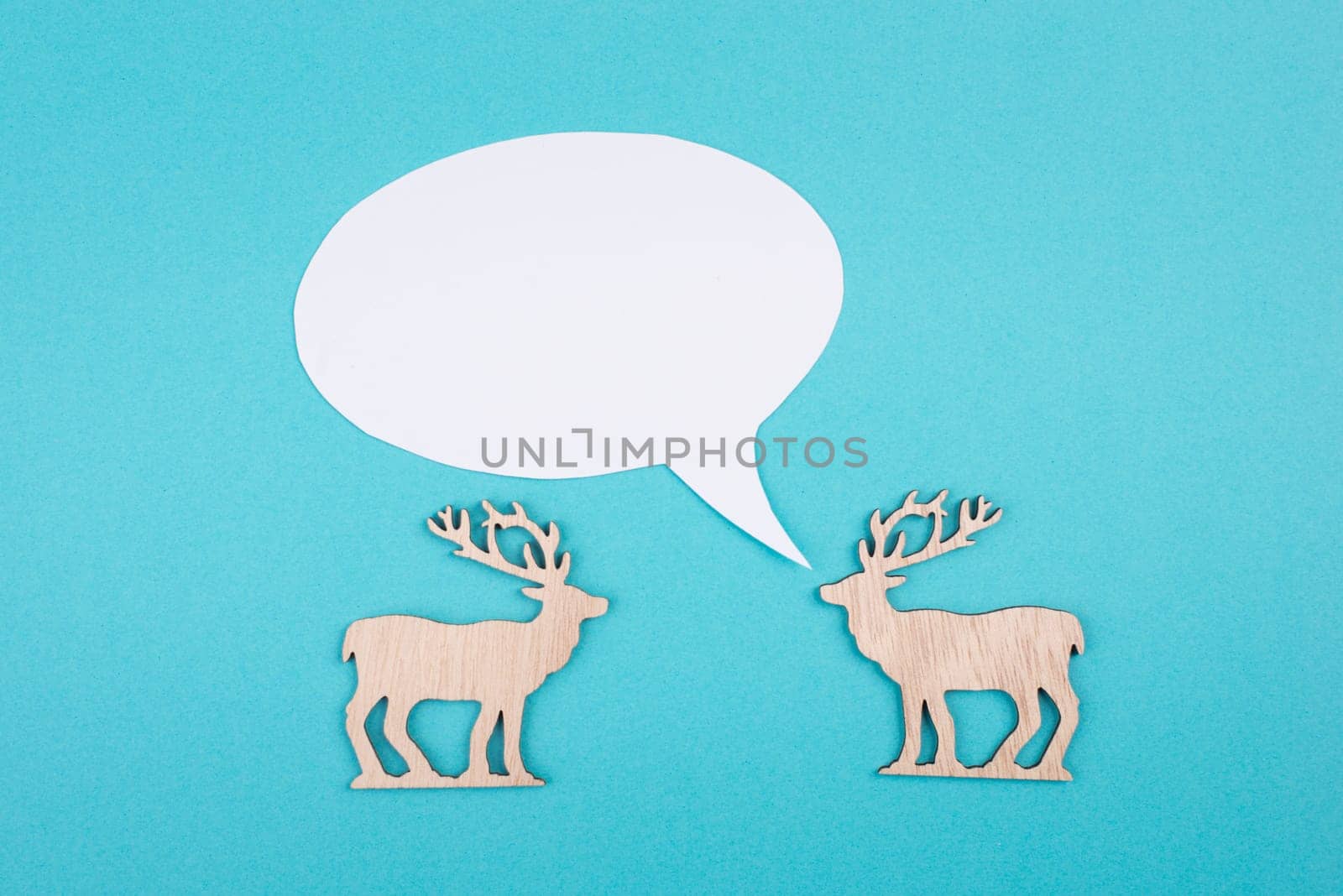 Two cute reindeers talking to each other, speech bubble with copy space, christmas greetings, blue colored background
