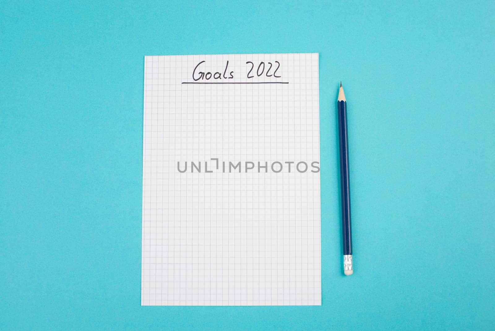Empty paper with goals 2022, copy space for text, pen, blue colored background, business concept, making plans for the new year