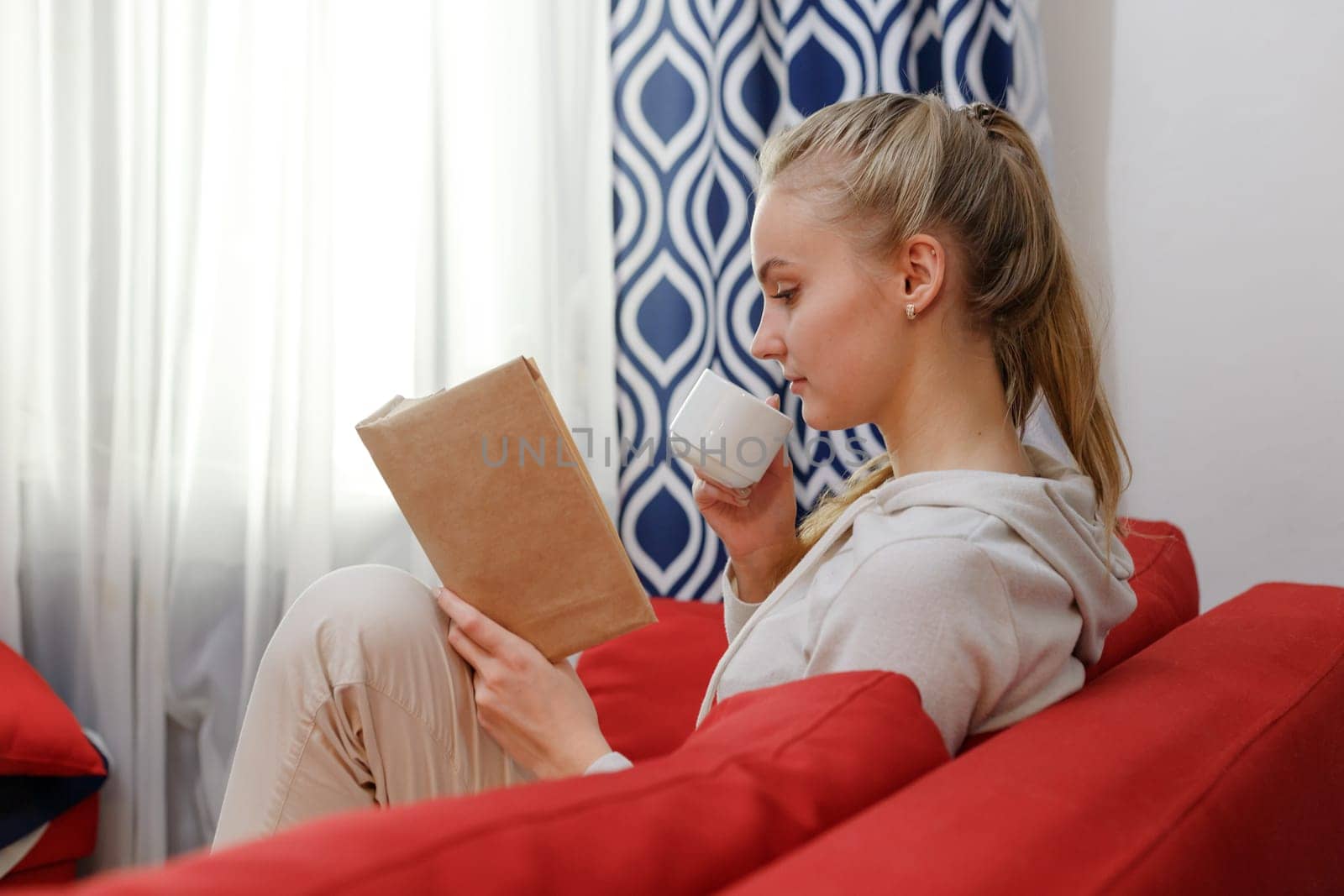 Soft photo of woman on the bed with old book and cup of coffee in hands, top view point. Education and self improvement