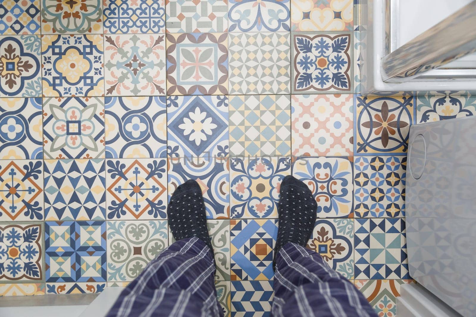 Man in warm socks stands on a cold ceramic tiled bathroom floor. Heating floor concept, winter. Underfloor heating is out of order