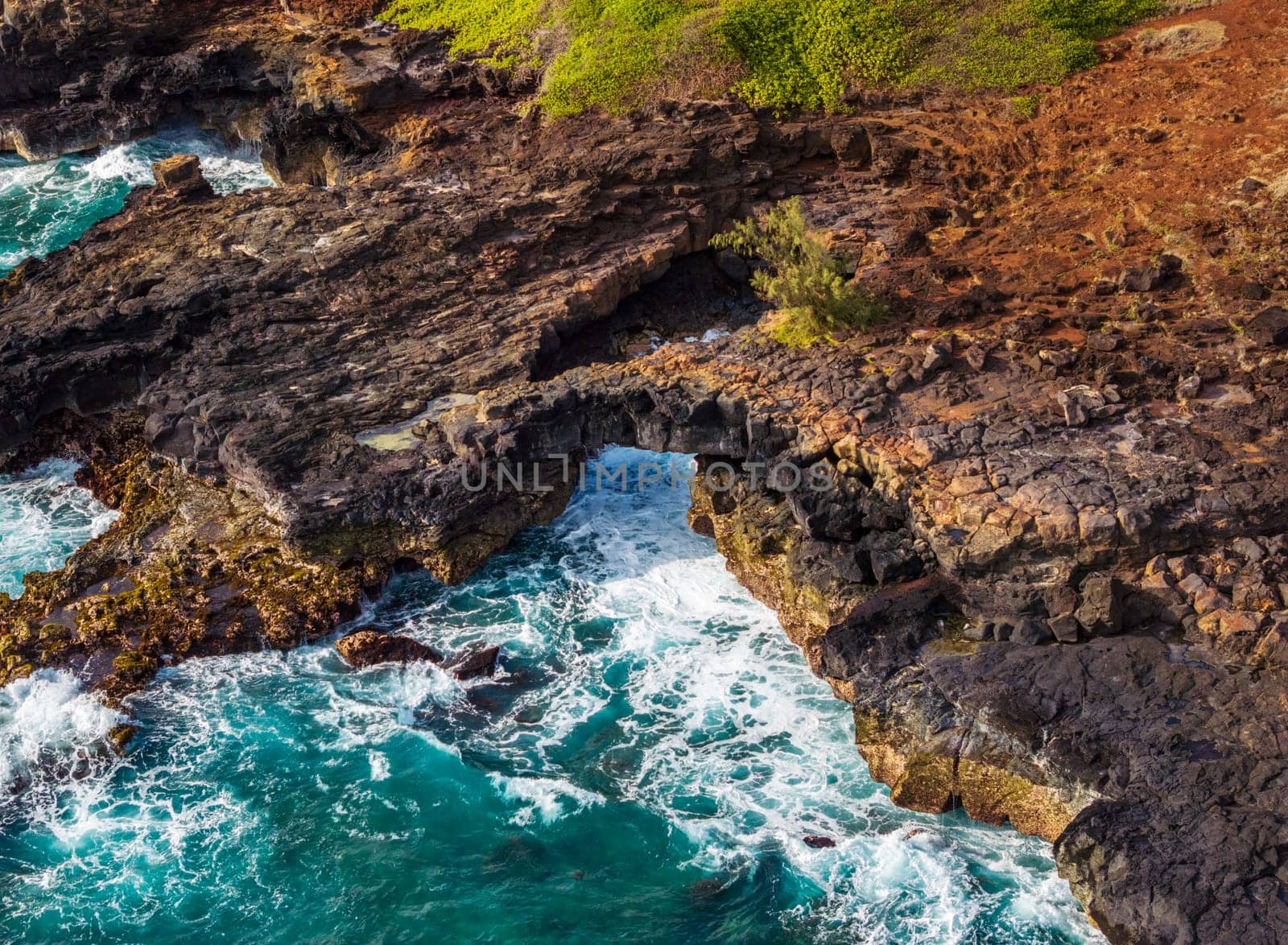 A natural lava arch provides a stunning contrast to the bright blue ocean at Poipu, Kauai, creating a beautiful coastal scene.