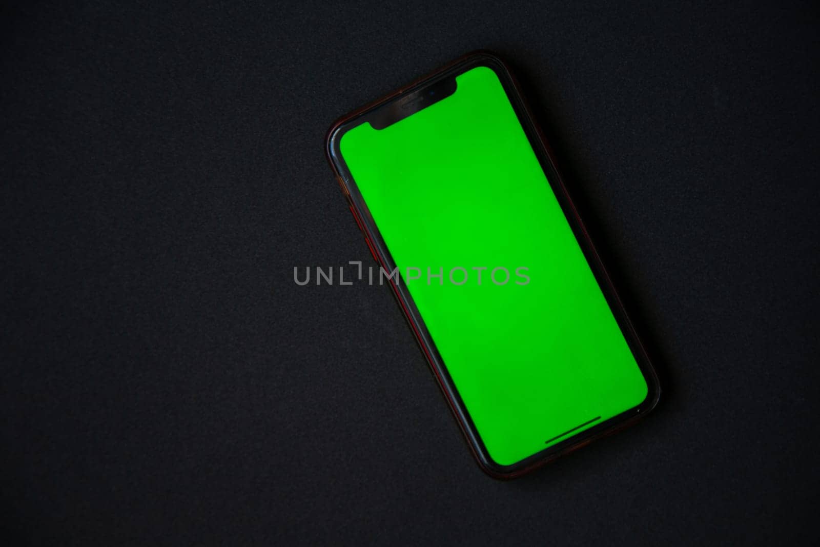 The phone with a green screen is on a black background. . High quality photo