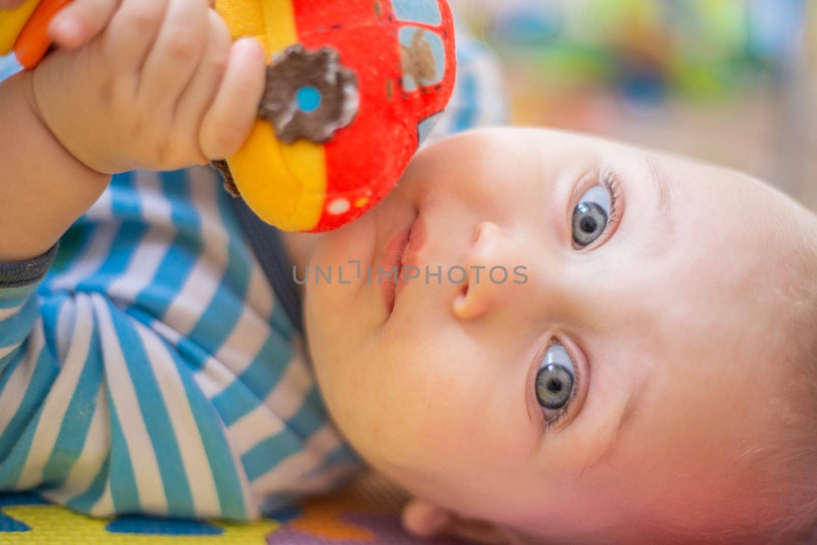 The little kid smiles and hugs the rattle machine to himself. High quality photo