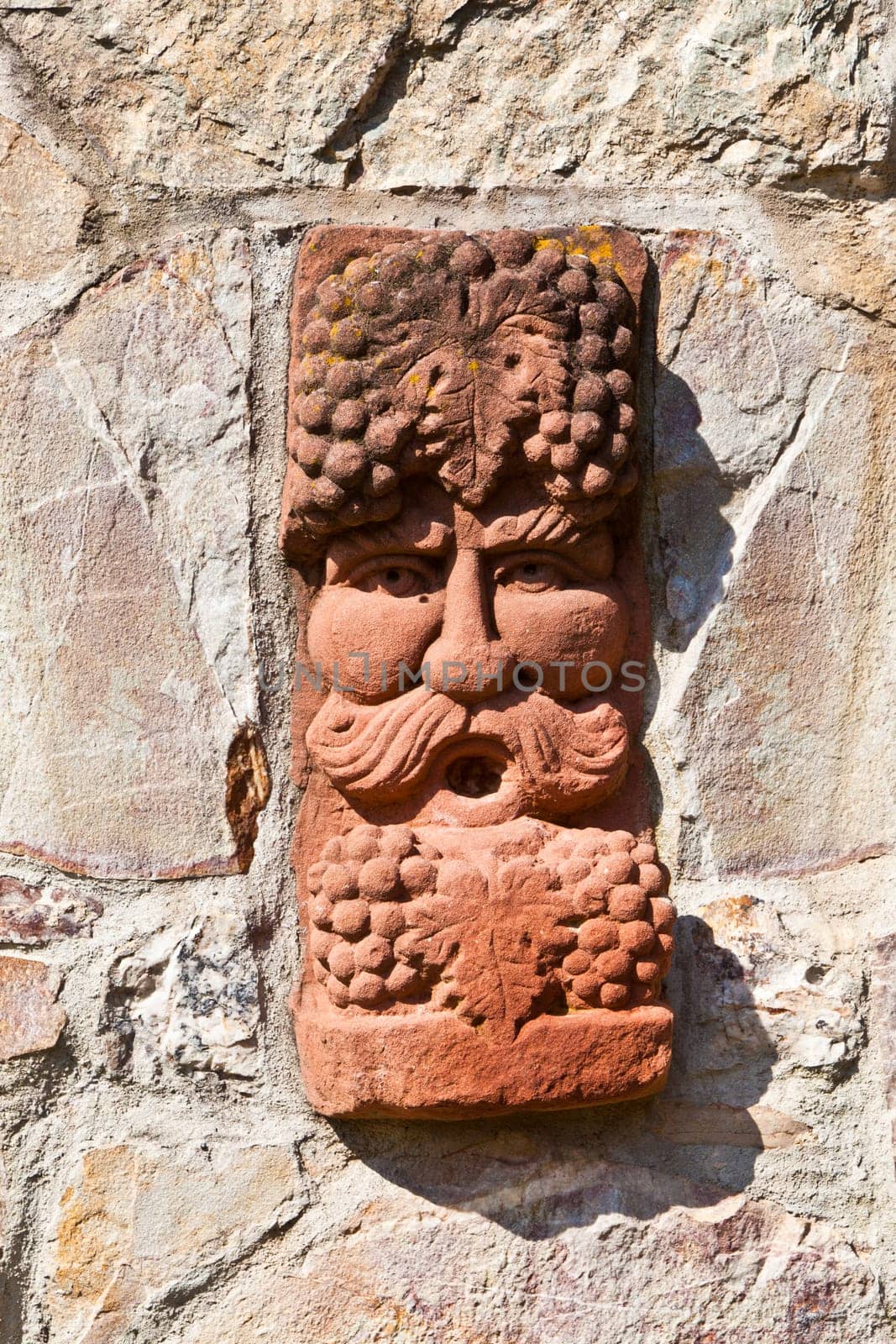 old medieval stone wall with face of baccus, the god of winery