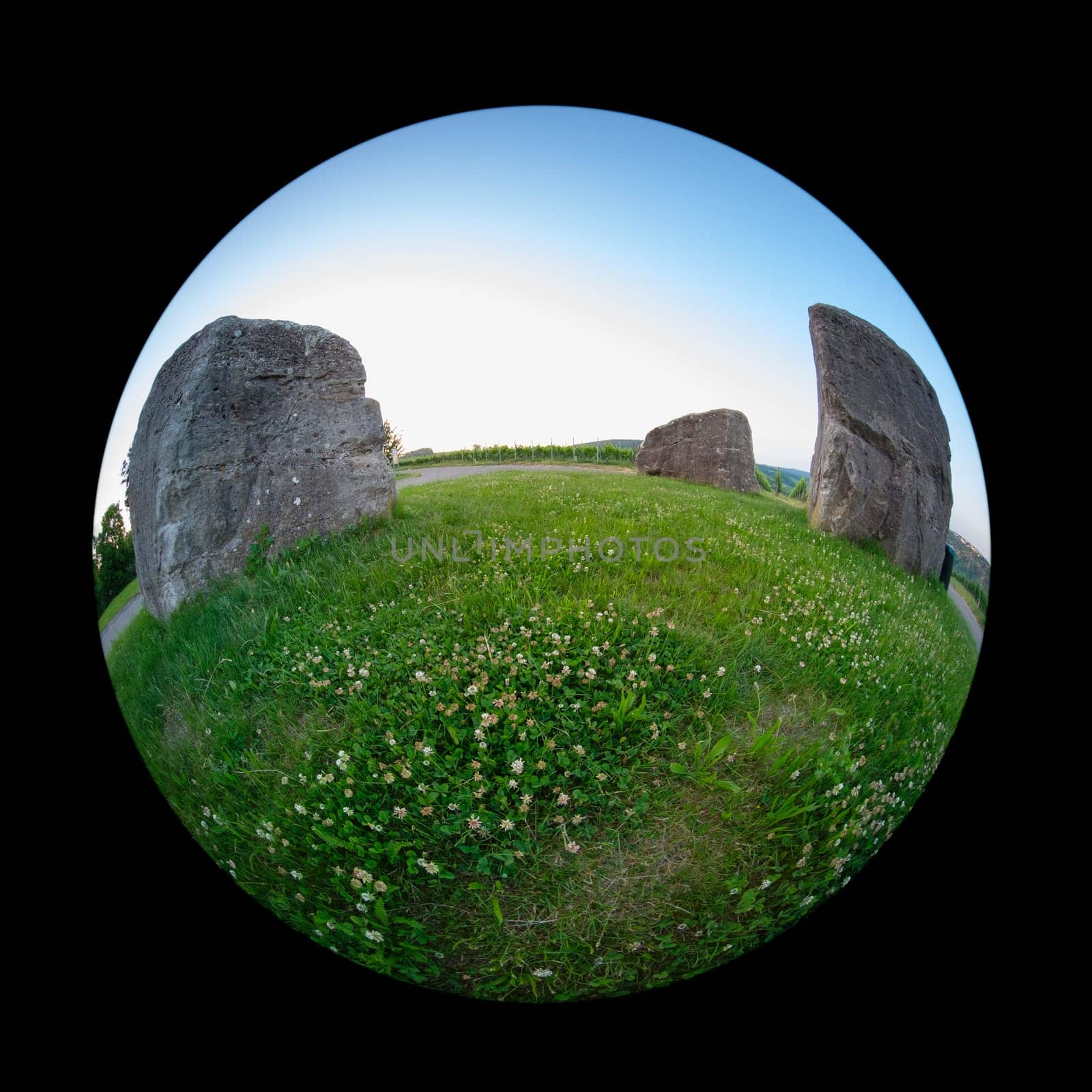 Three rocks on green meadow with fish-eye distortion