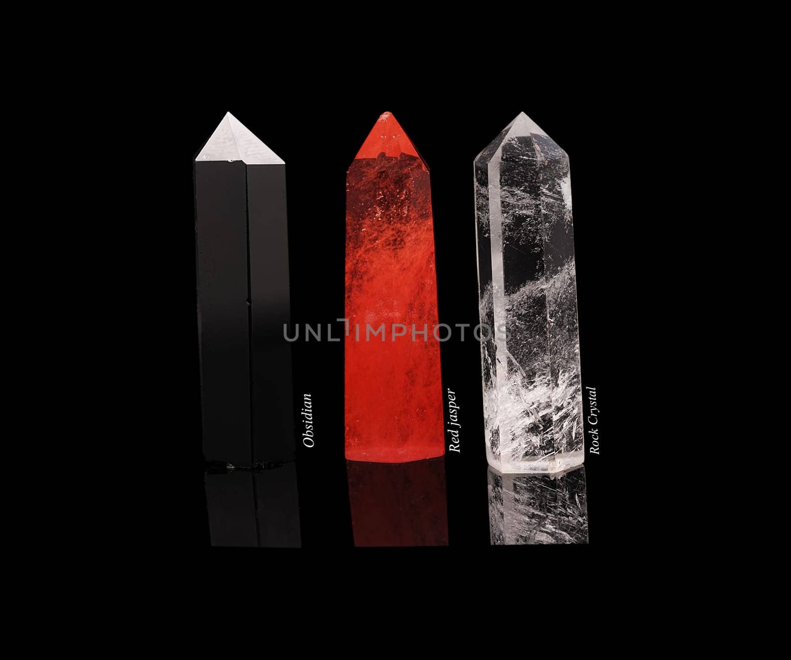 Set of crystals of semi-precious stones: obsidian, rhinestone, red jasper with natural reflection isolated on black glossy background