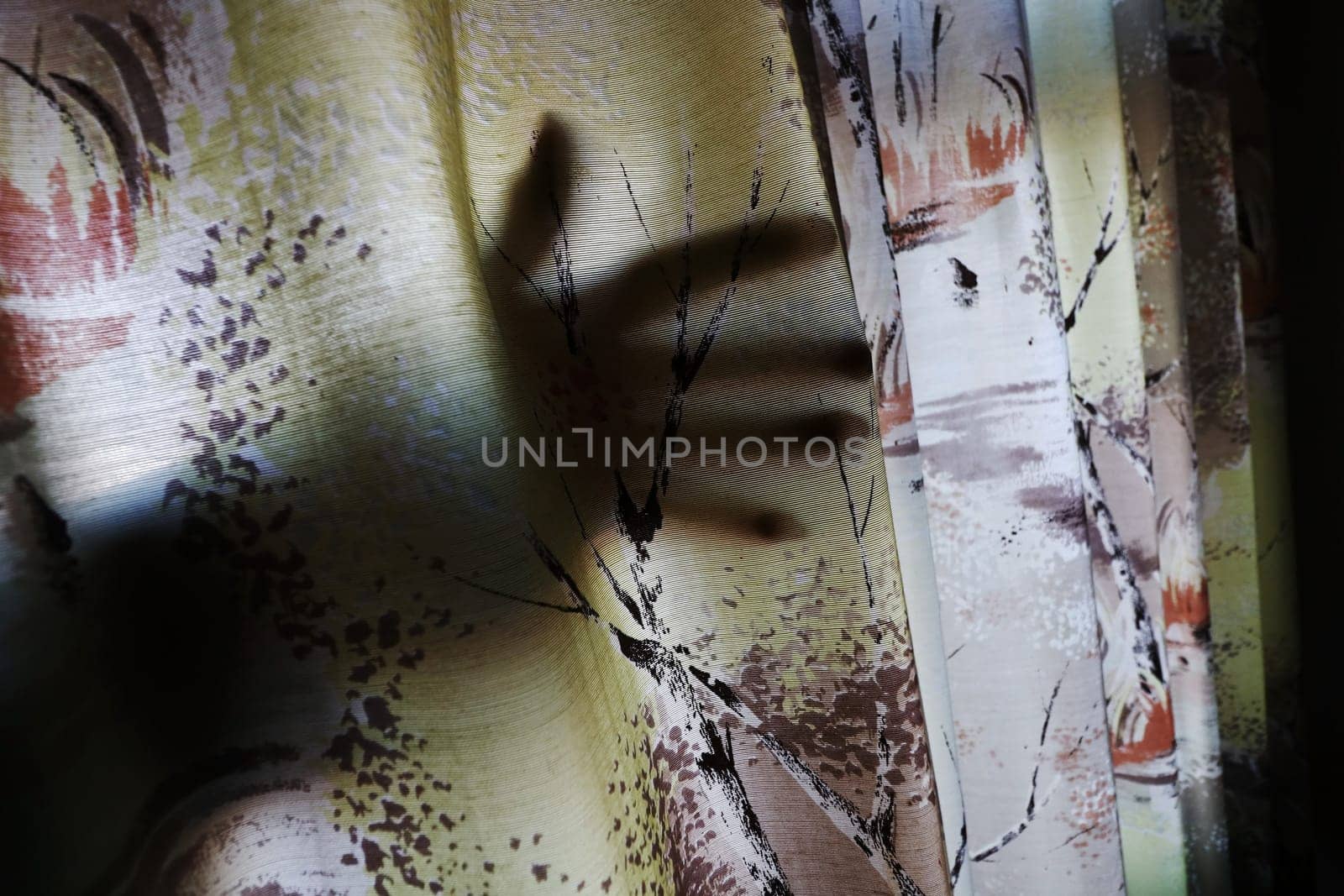 A creepy hand behind a curtain. The hand of a burglar through an open window