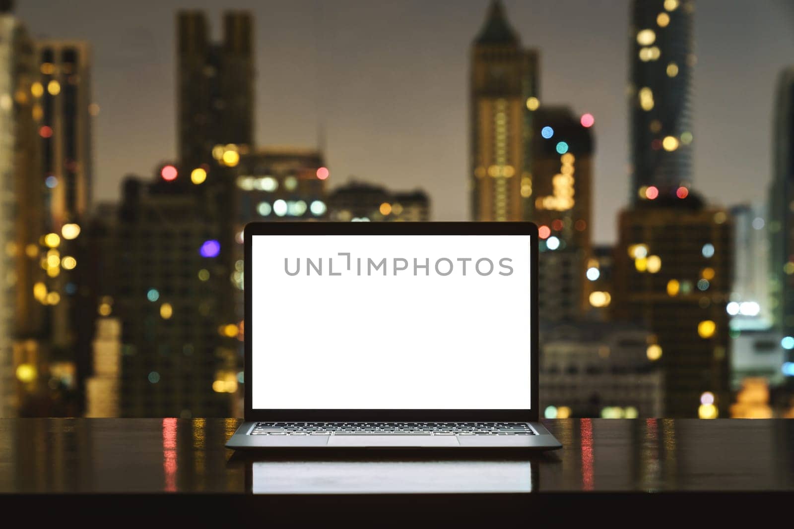 laptop computer on workspace white blank screen display city on night background