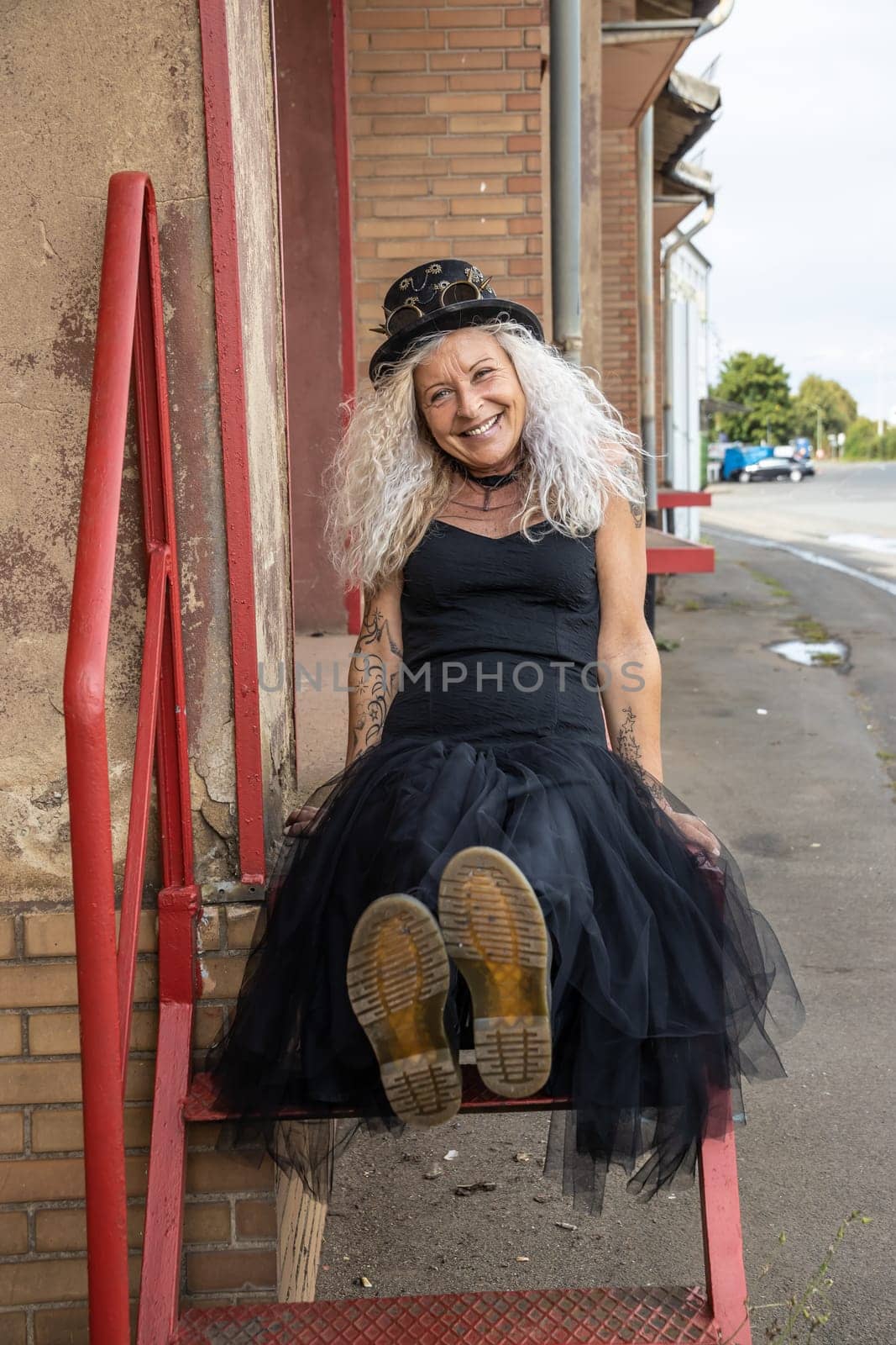 Casual Woman in the 50s wearing Steampunk Look sitting on a old loading dock