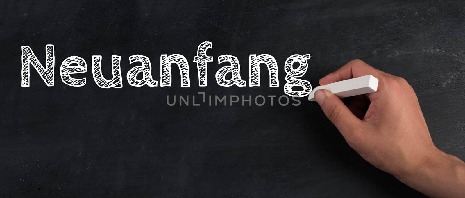The words new start are standing on a chalkboard, hand writing, german language
