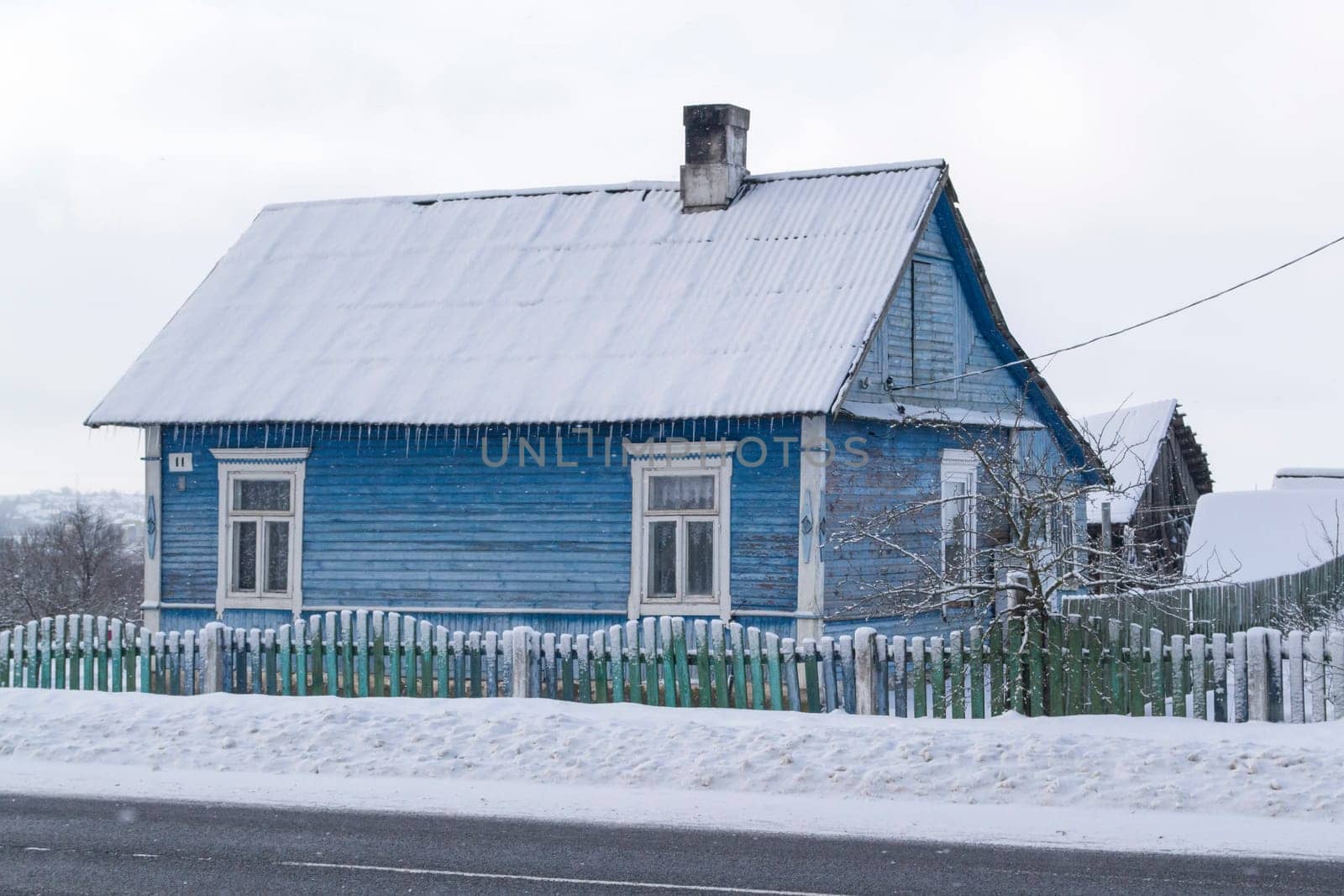Typical old blue wooden house in snow of winter day